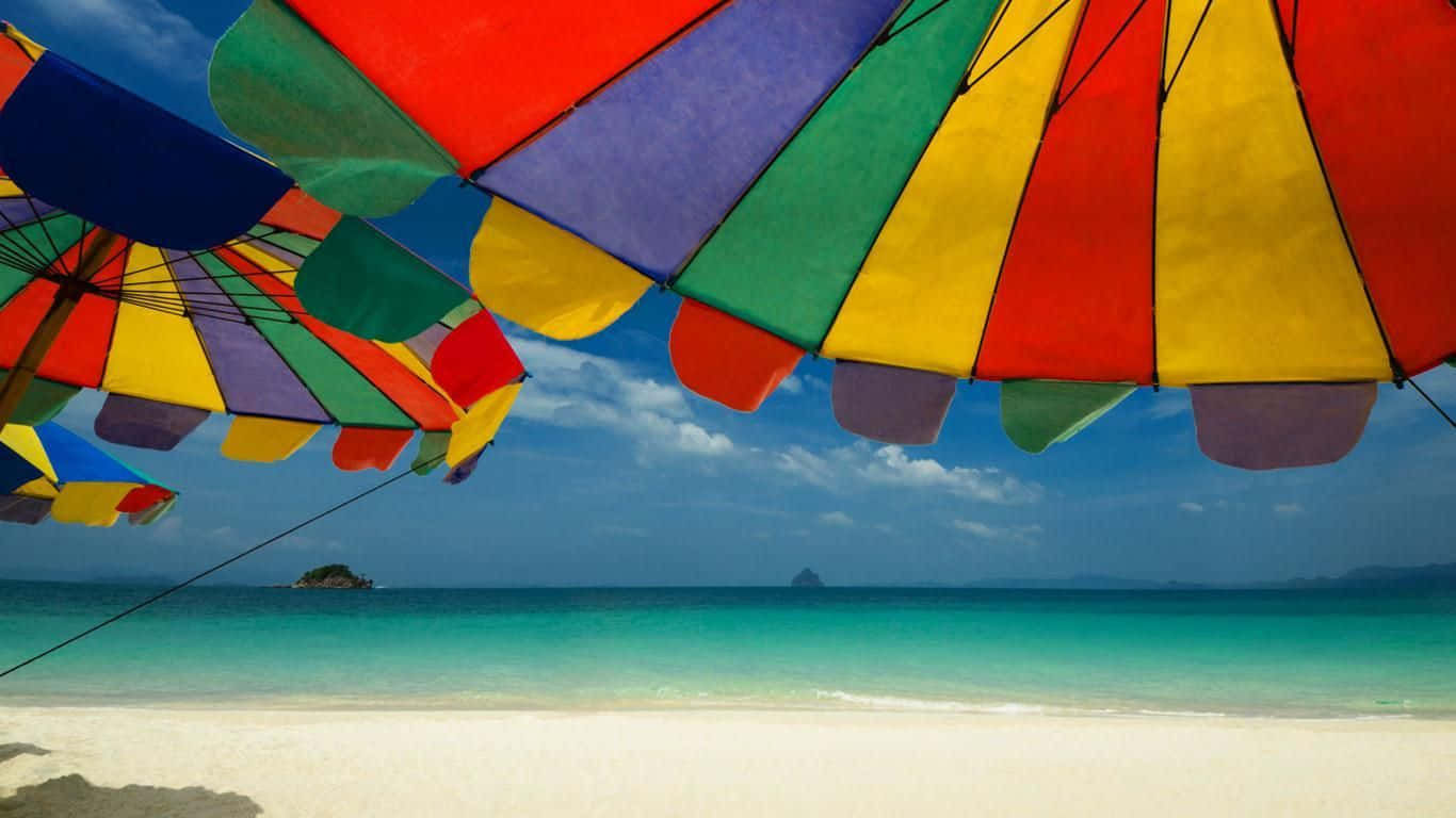 A Relaxing Day at the Beach with a Colorful Beach Umbrella Wallpaper