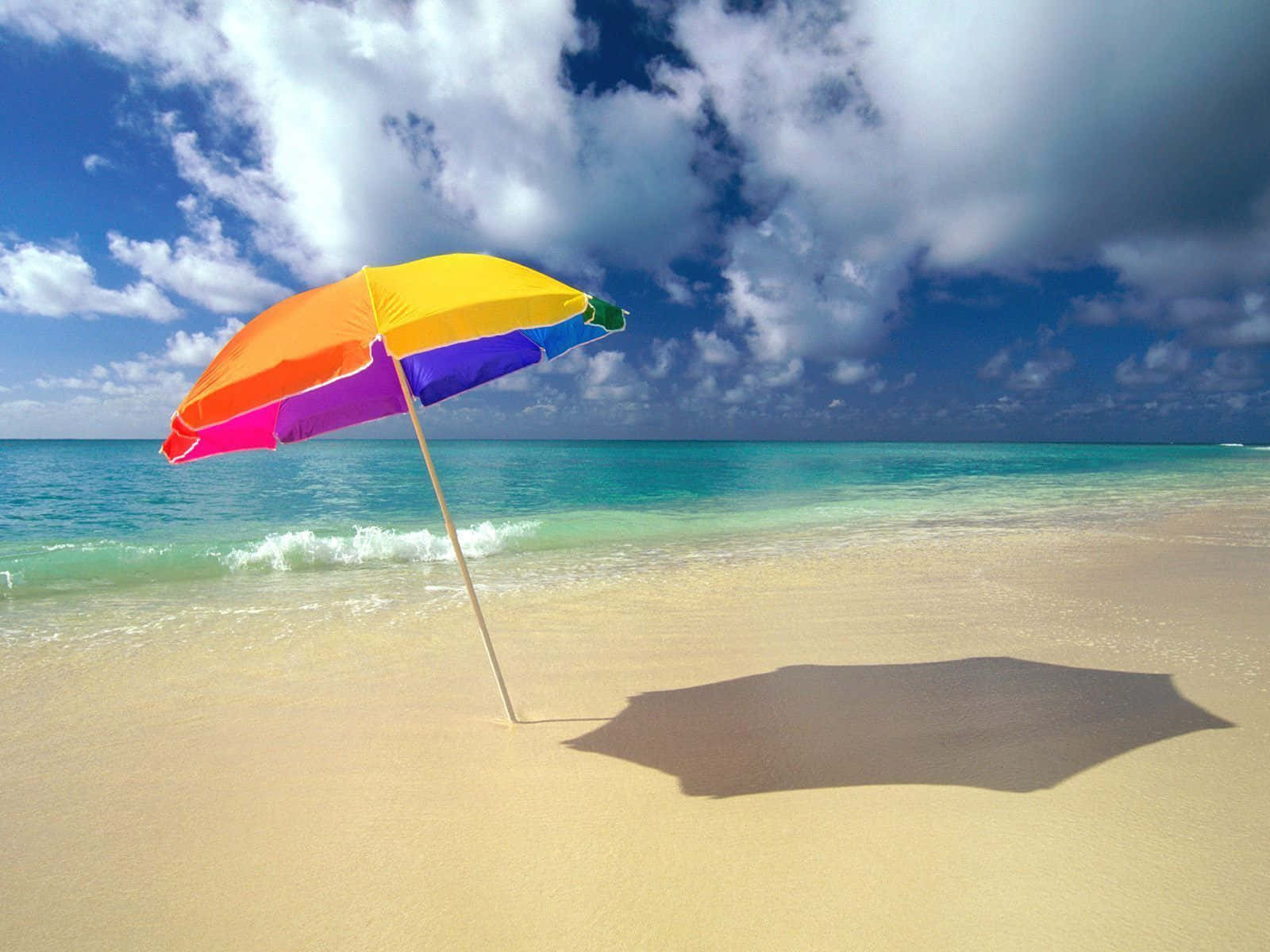 Vibrant Beach Umbrella Providing Shade on a Sunny Day Wallpaper