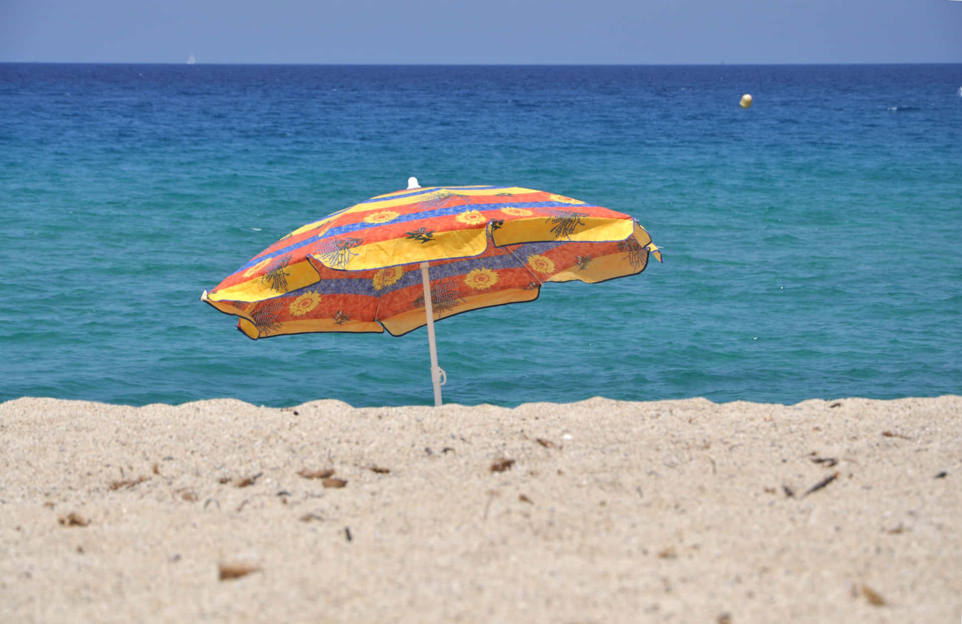 Caption: Vibrant Beach Umbrella on a Sunny Day Wallpaper