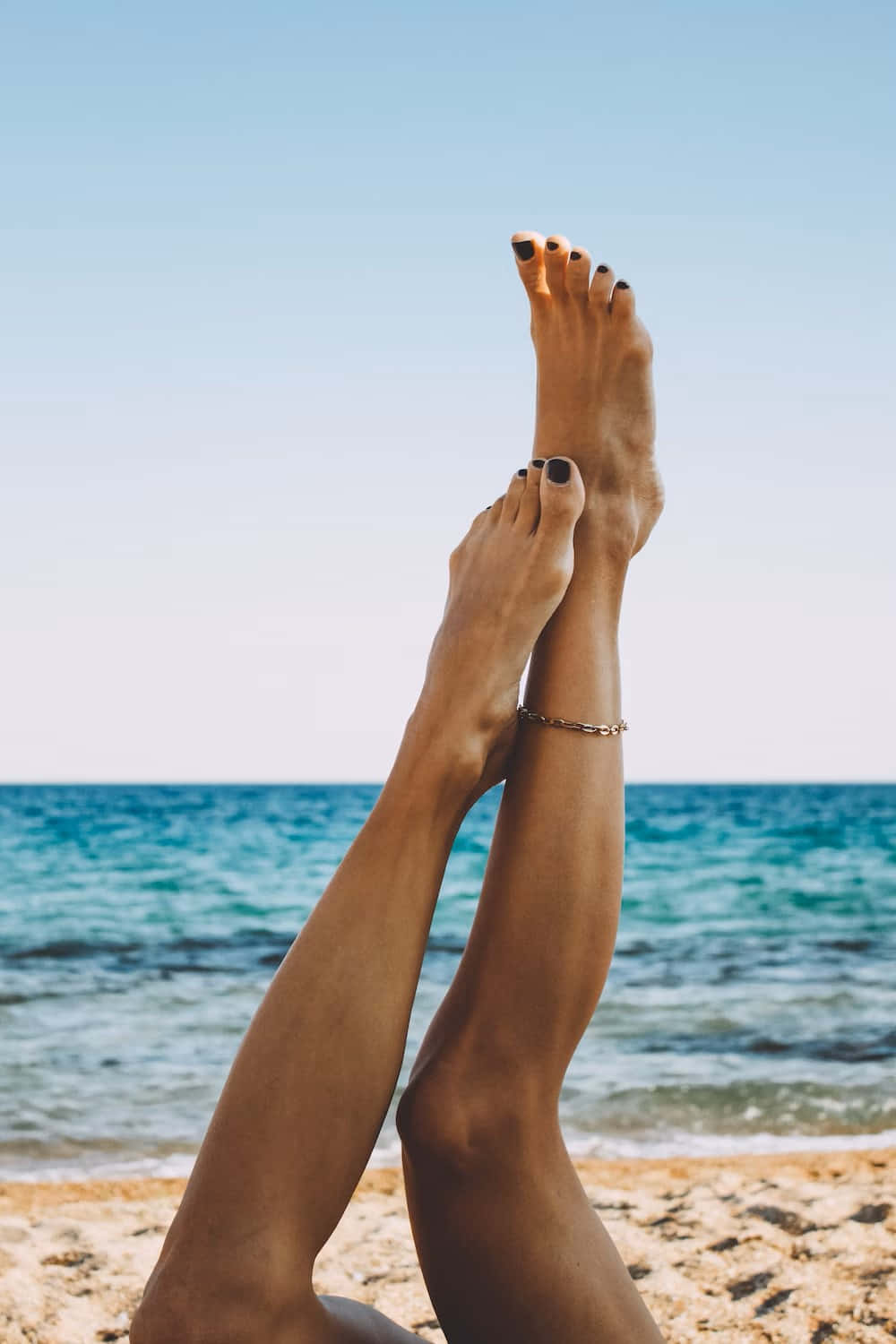 Beachside Legs Raised Against Sky Wallpaper