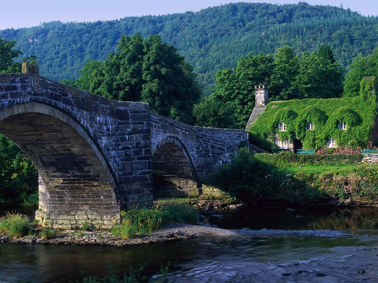 a stone bridge over a river with a house on it
