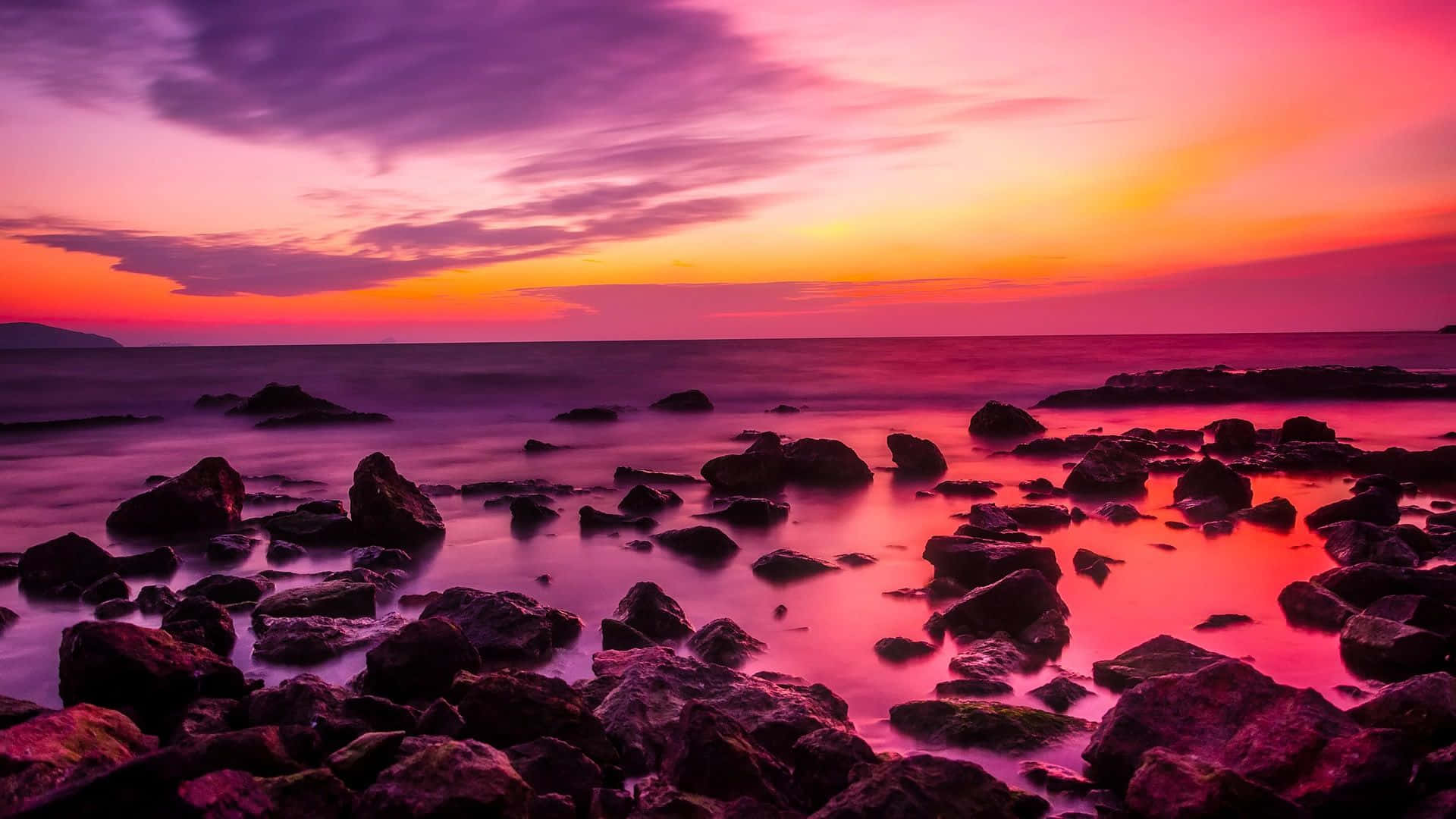 a sunset with rocks and a colorful sky