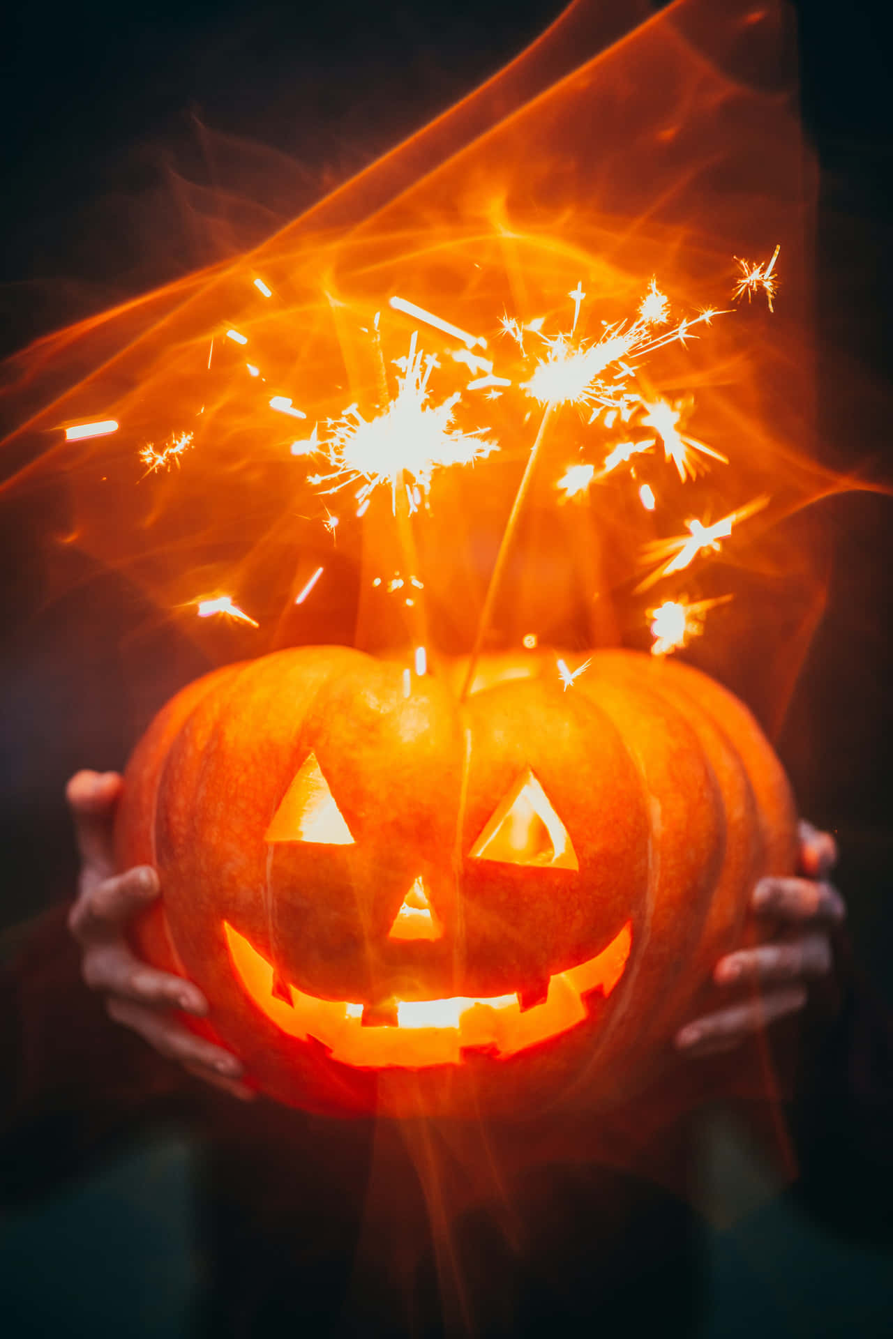 A Person Holding A Pumpkin With Sparklers In It Wallpaper