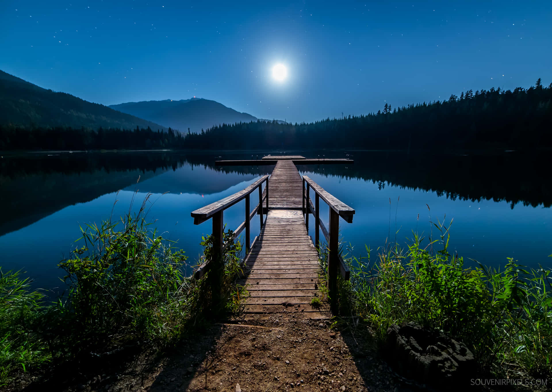 A Wooden Dock Over A Lake At Night Wallpaper
