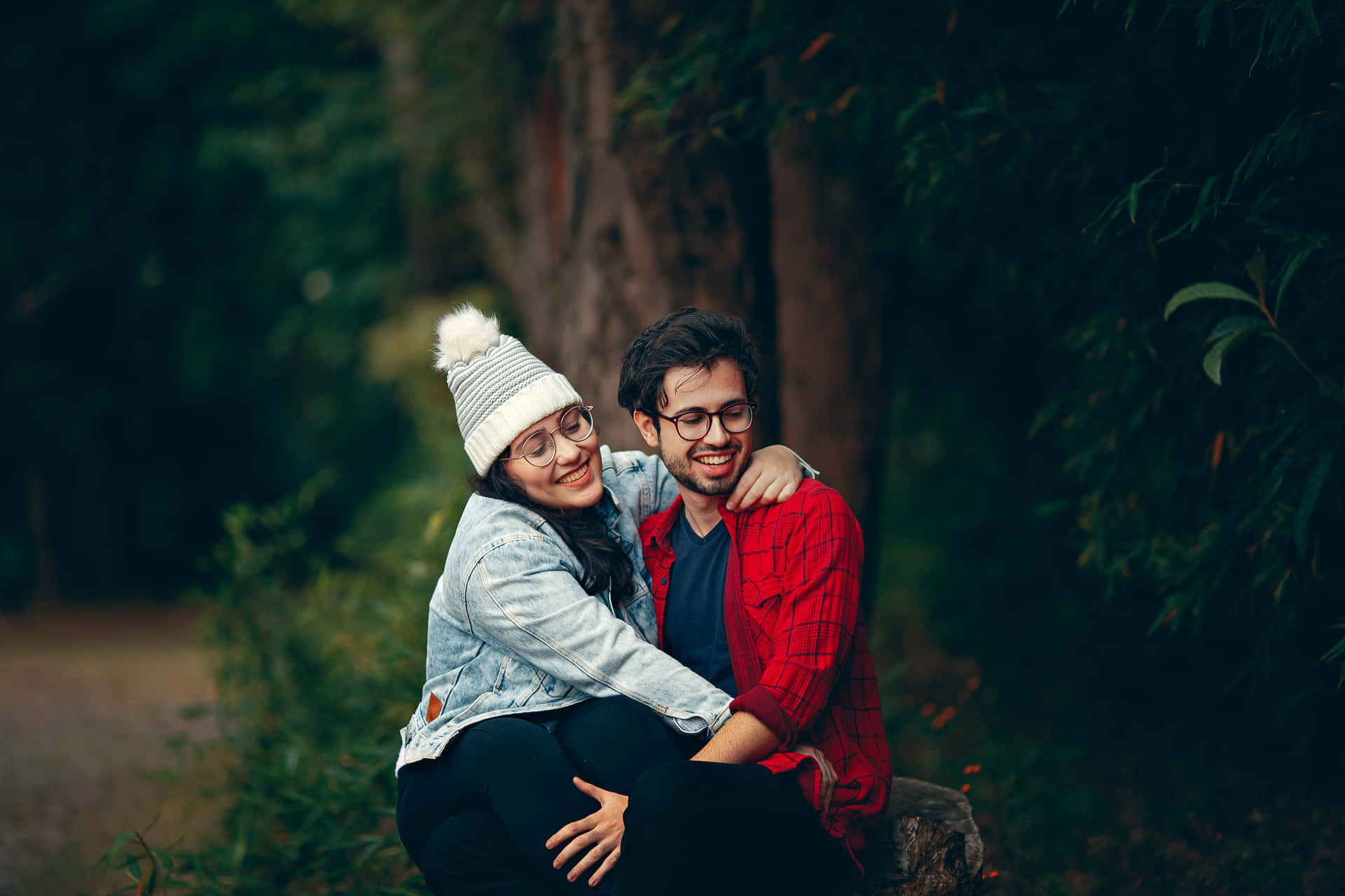 Et par, der sidder på en log i skoven. Wallpaper