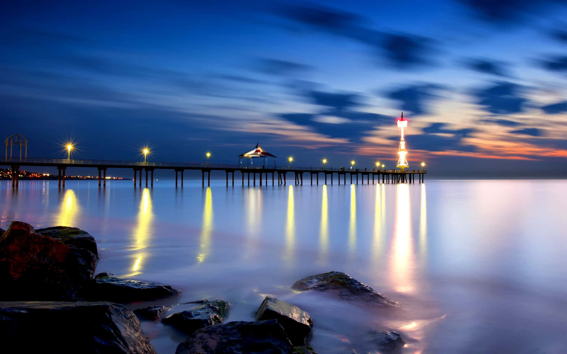 A Pier With Rocks And Water At Dusk