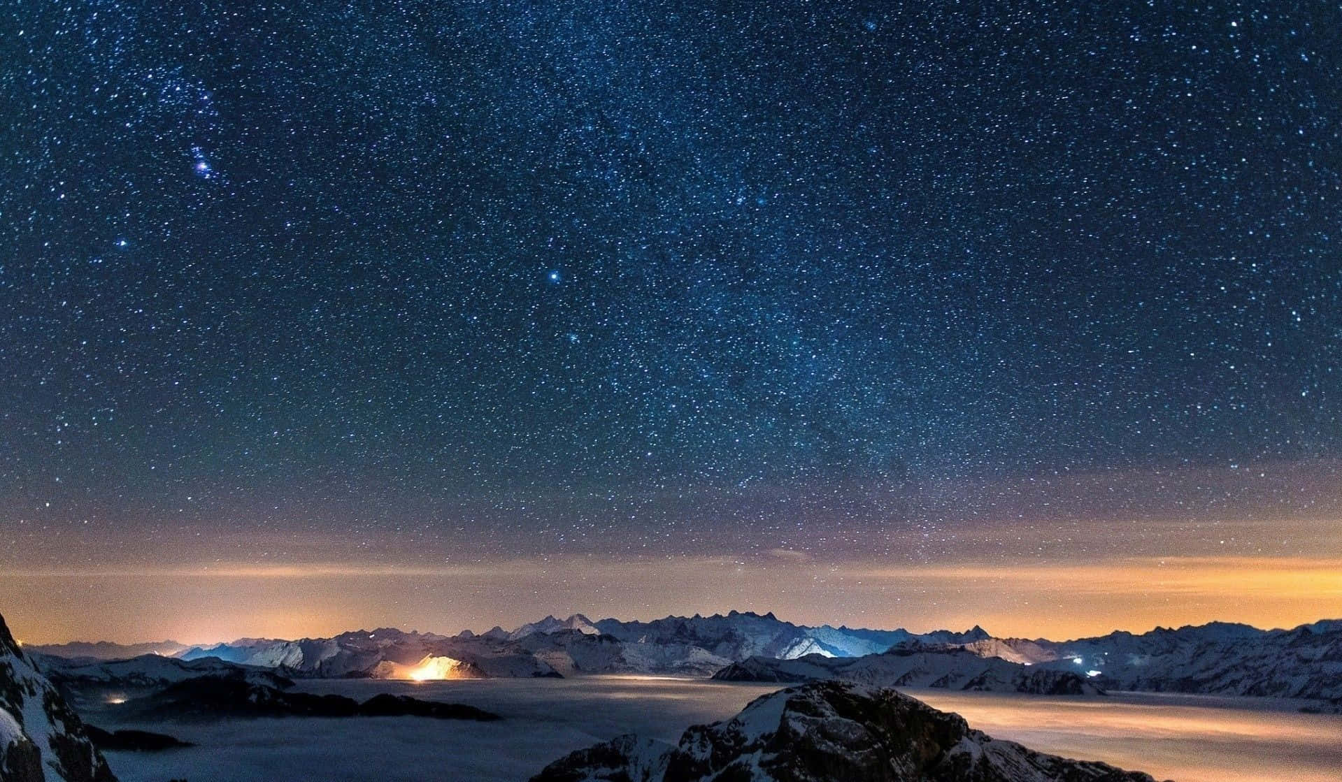 A Night Sky With Stars And Clouds Above A Mountain