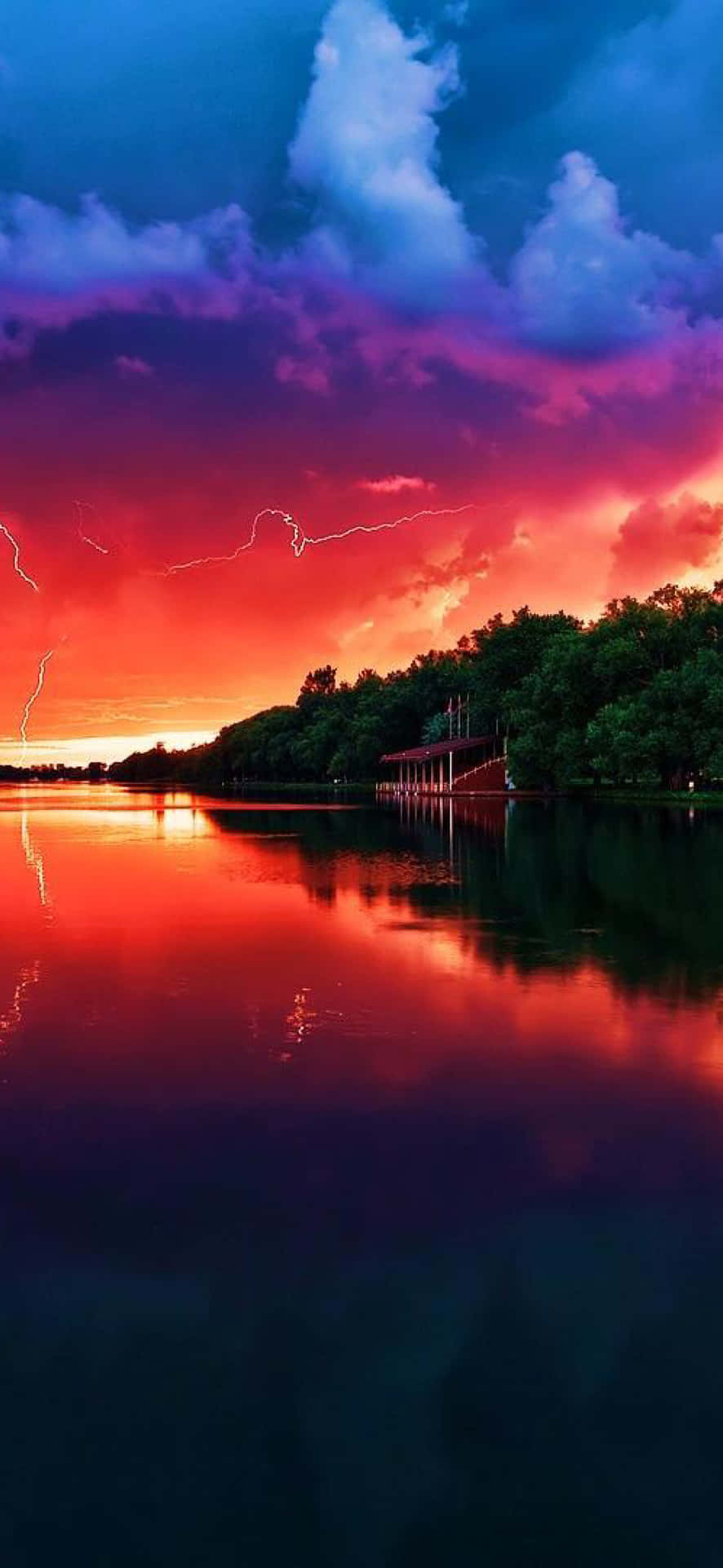 Et farverigt solnedgang over en sø med lyn. Wallpaper