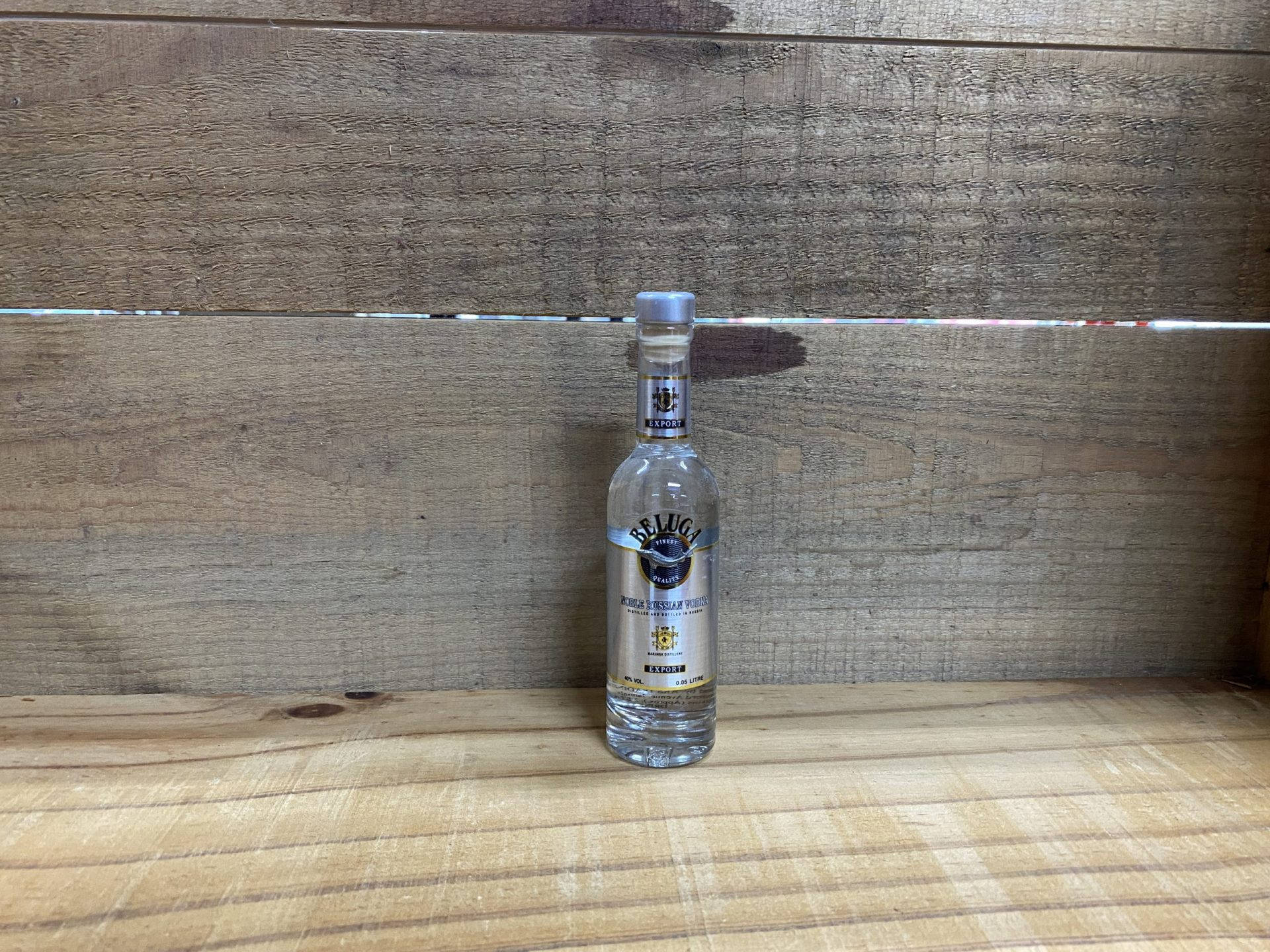 Caption: Elegant Beluga Vodka Bottle on Classic Wood Floor Wallpaper