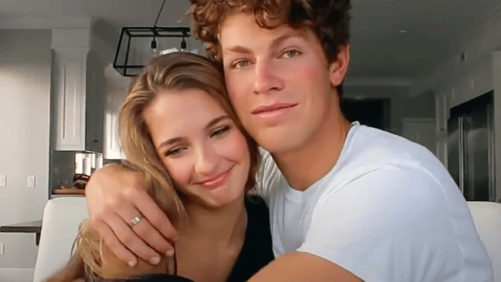 A Young Man And Woman Hugging On A Couch