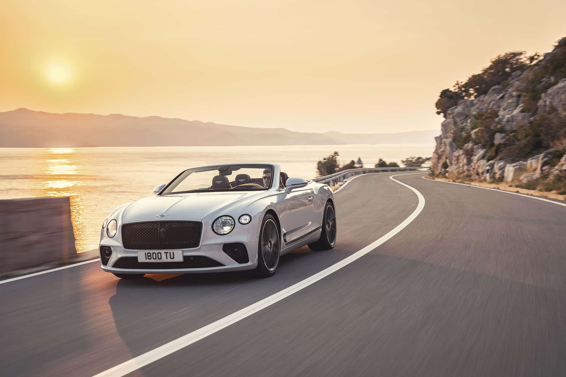 Luxurious Bentley Continental GT Convertible cruising on an open road Wallpaper