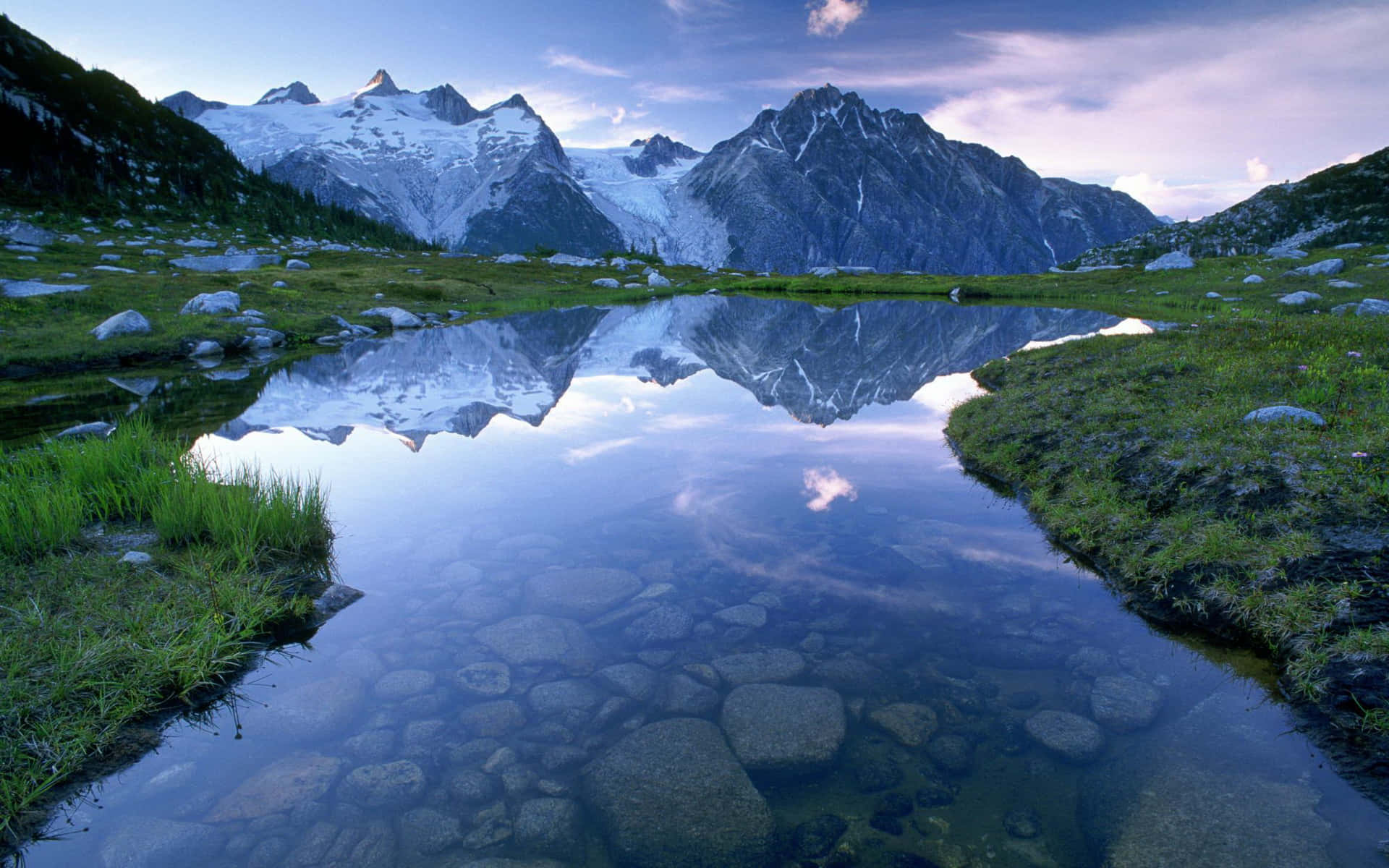 a lake surrounded by mountains and grass