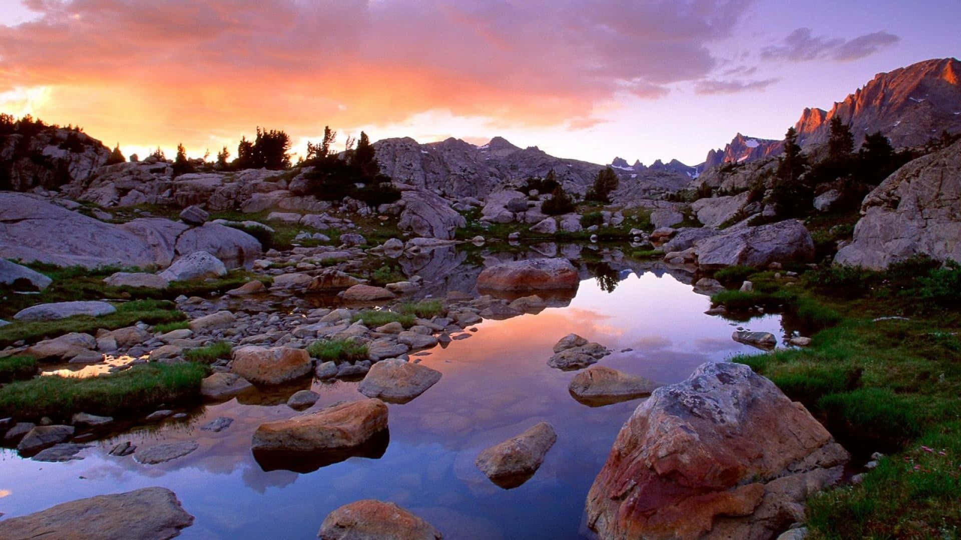 a mountain lake with rocks and a sunset