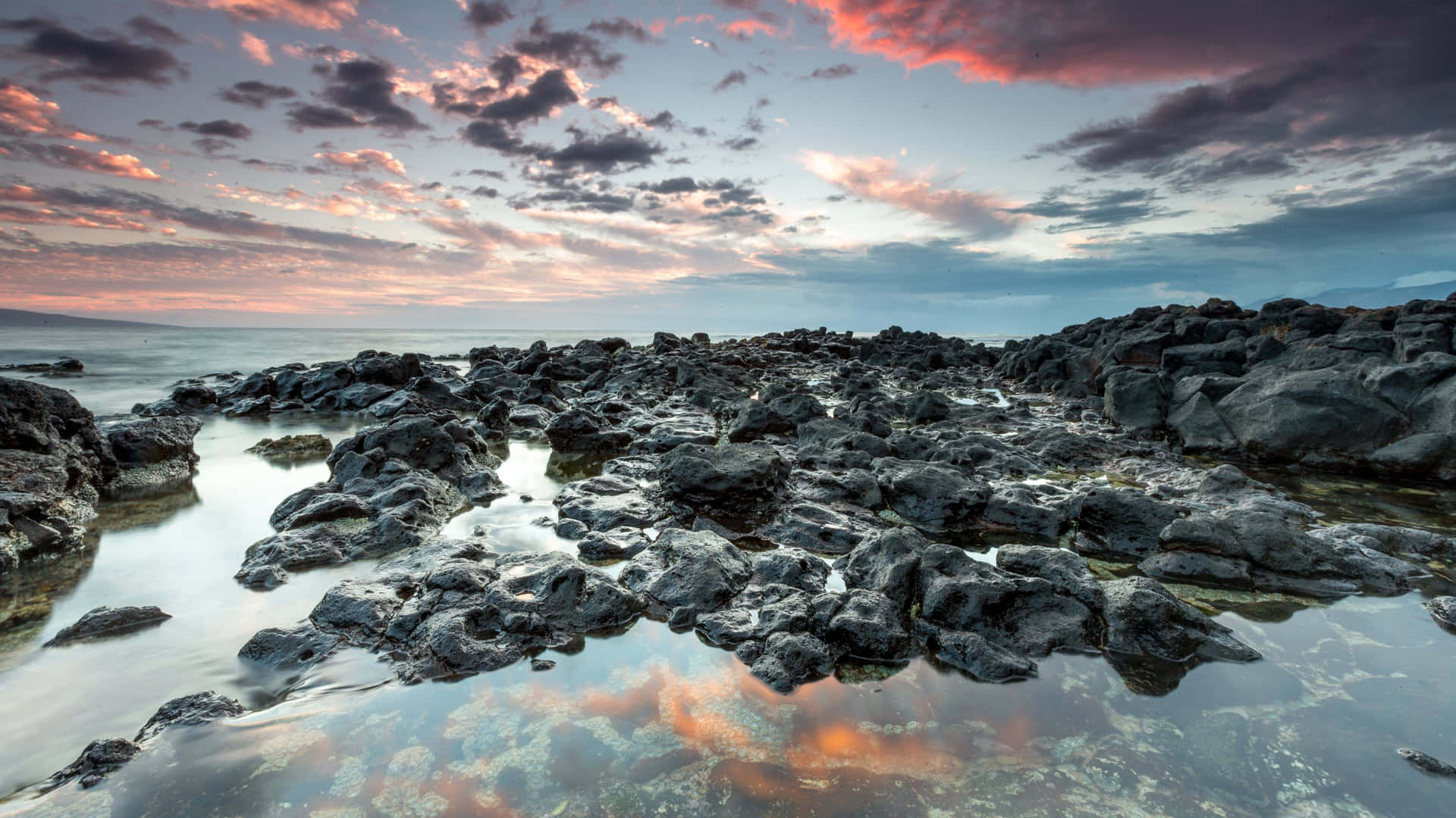 a rocky shore with a sunset sky