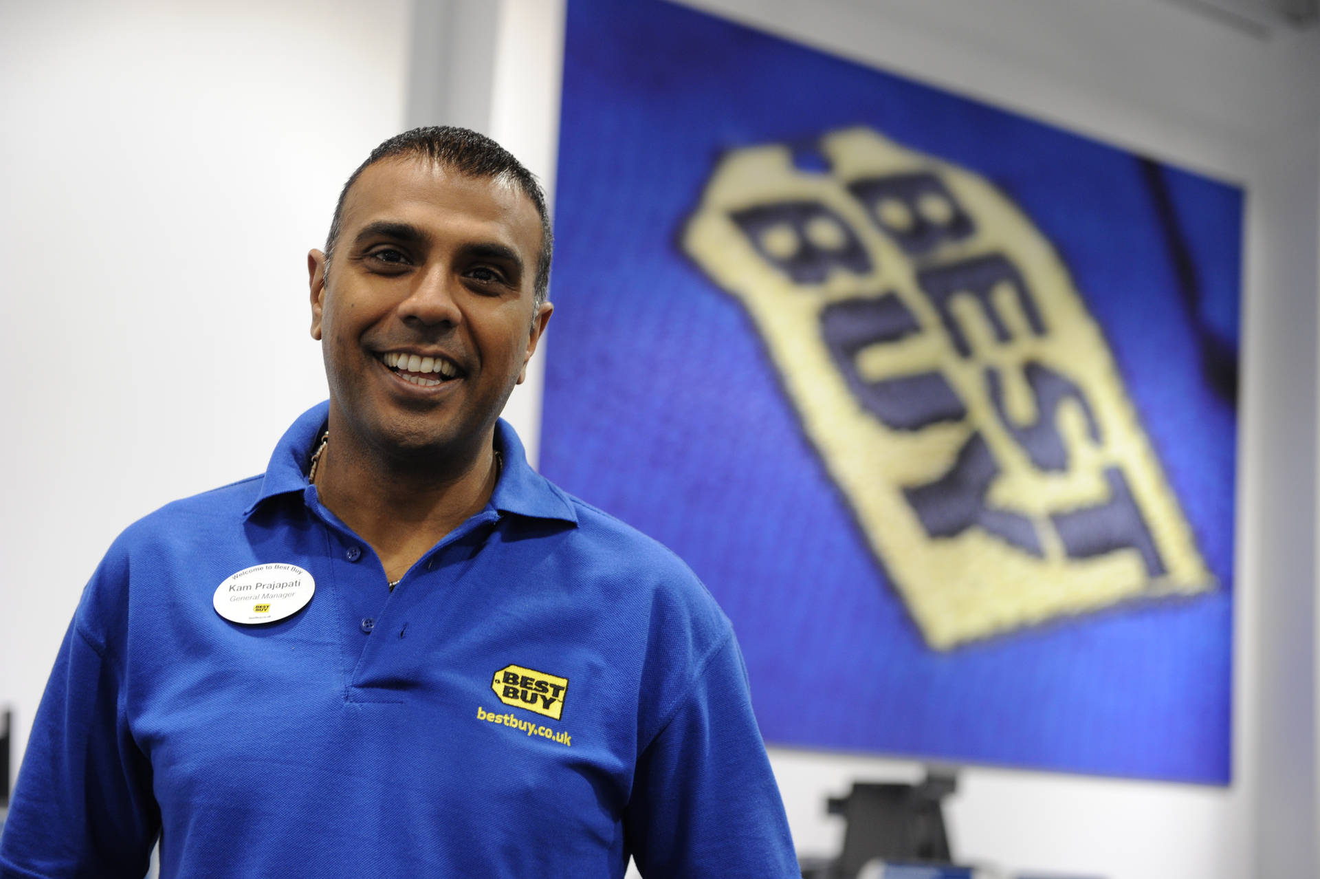 Enthusiastic Best Buy Employee Ready to Assist Customers Wallpaper