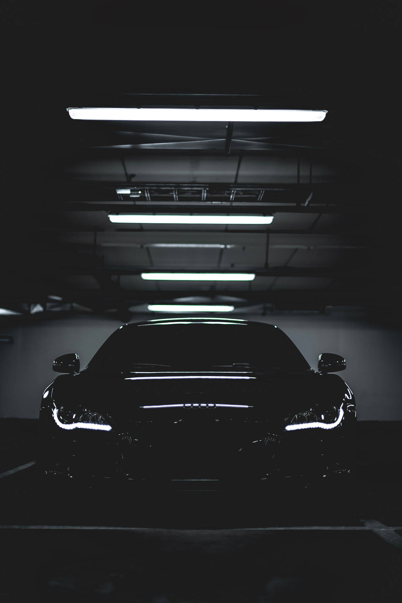 En sort bil i en mørk parkeringsgarage. Wallpaper