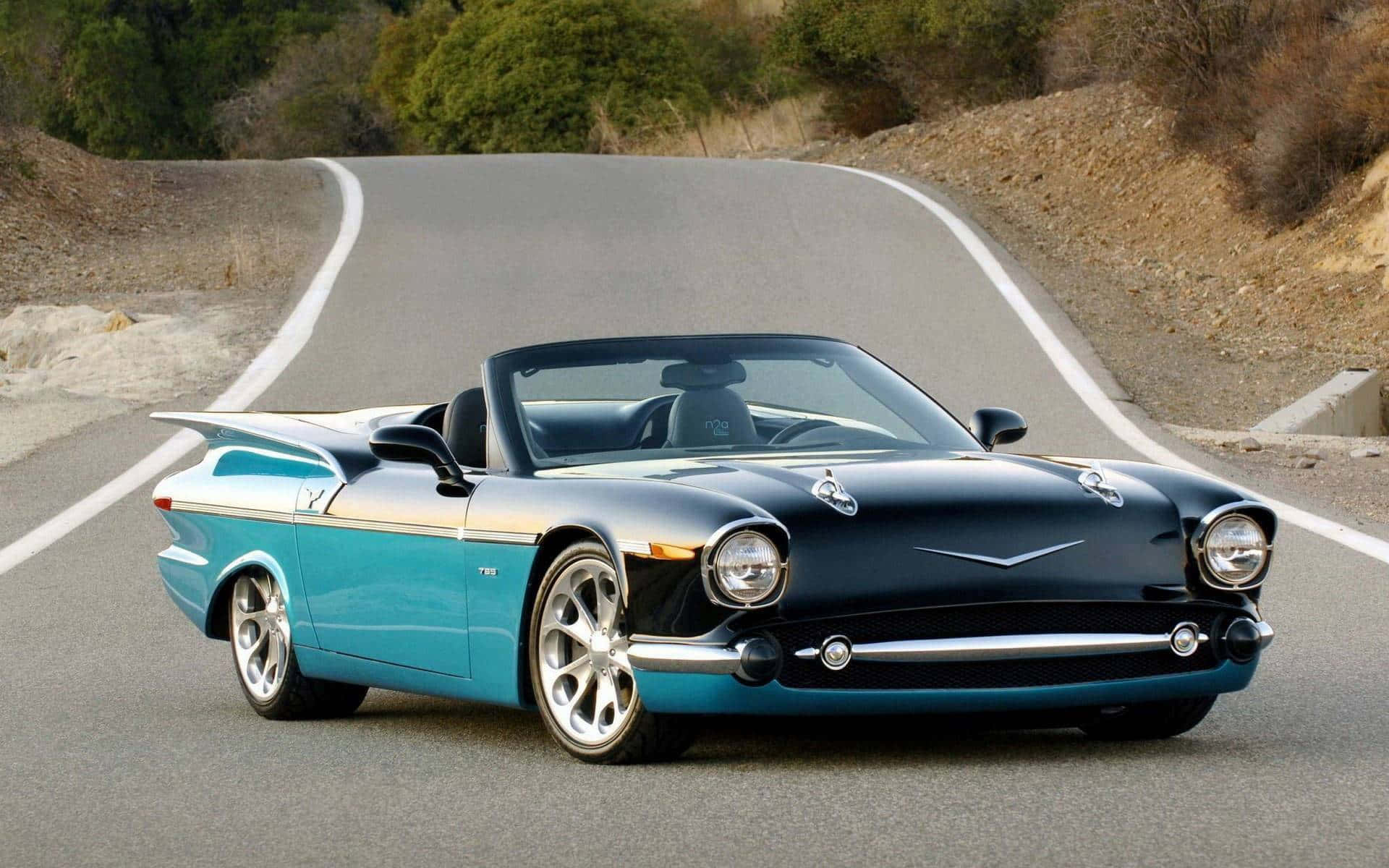 A Blue And Black Convertible Car Is Driving Down A Road