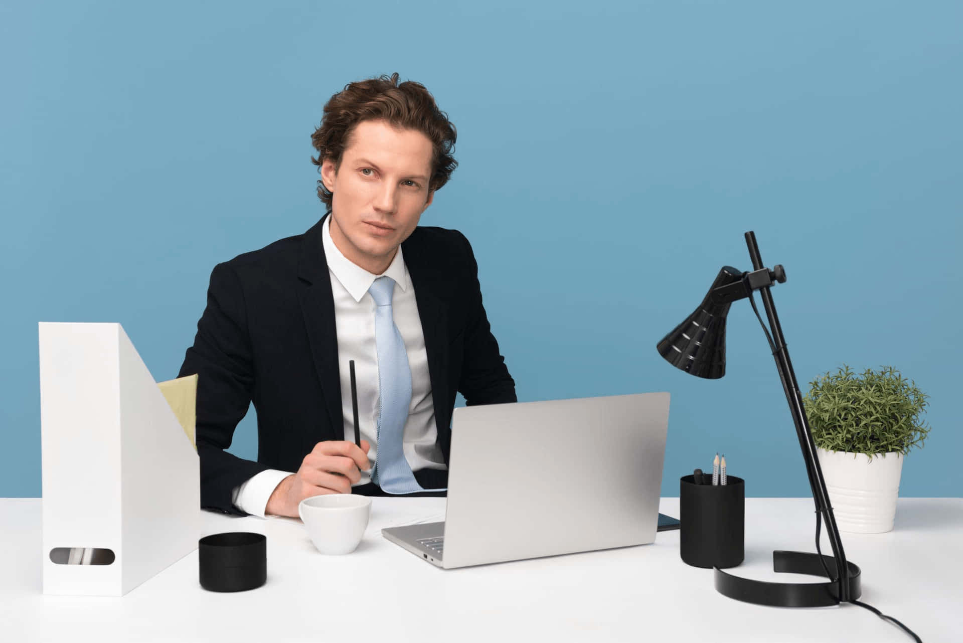 En forretningsmand sidder ved sit skrivebord med en bærbar computer og en pen.