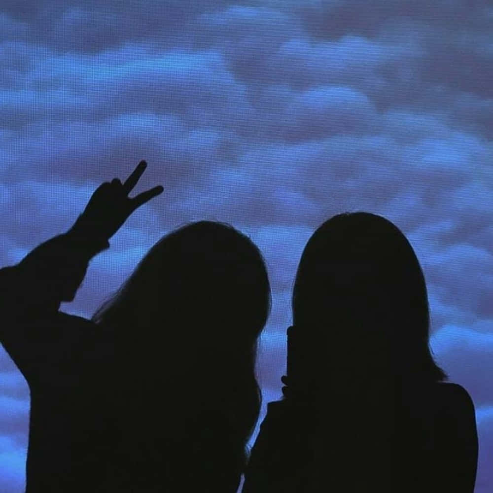 To skygger af kvinder, der holder deres hænder foran en blå himmel Wallpaper