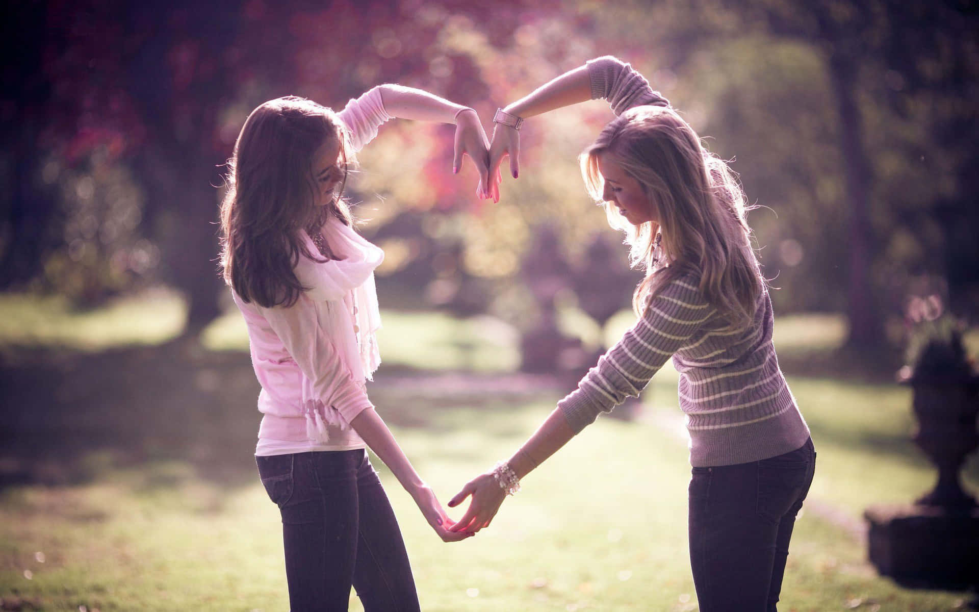 Two Girls Holding Hands In A Heart Shape Wallpaper