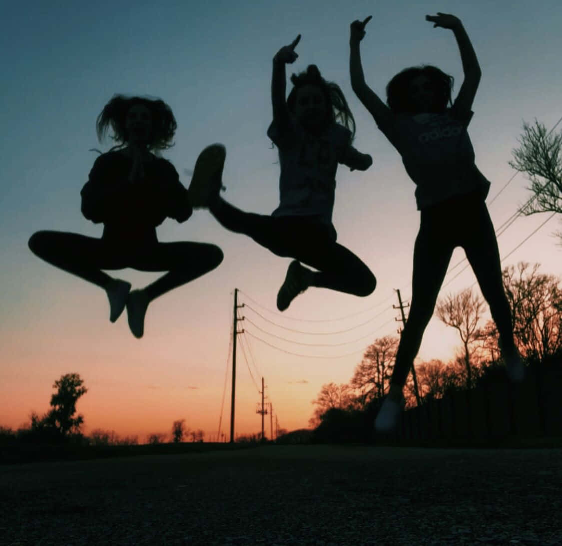 Three Girls Jumping In The Air At Sunset