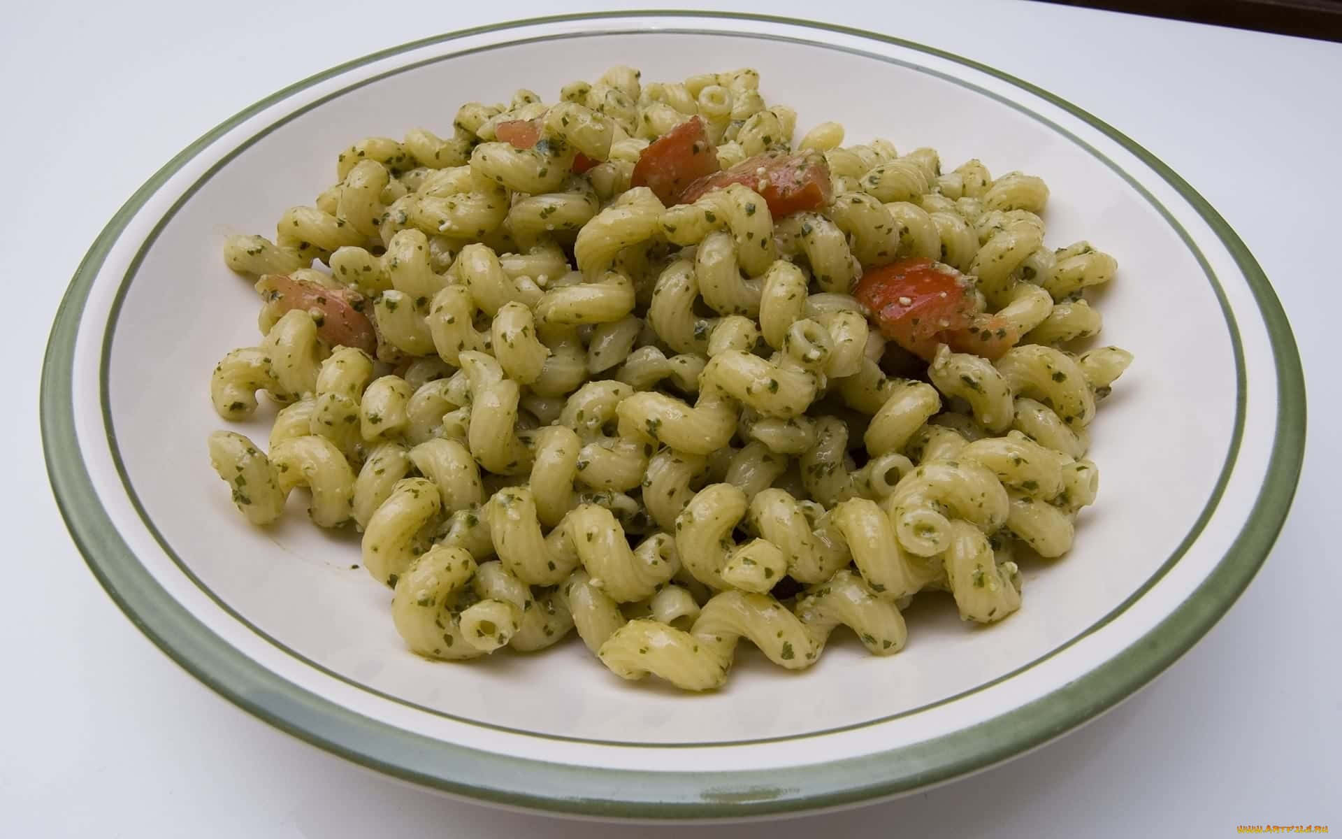 A Bowl Of Pasta With Pesto And Tomatoes