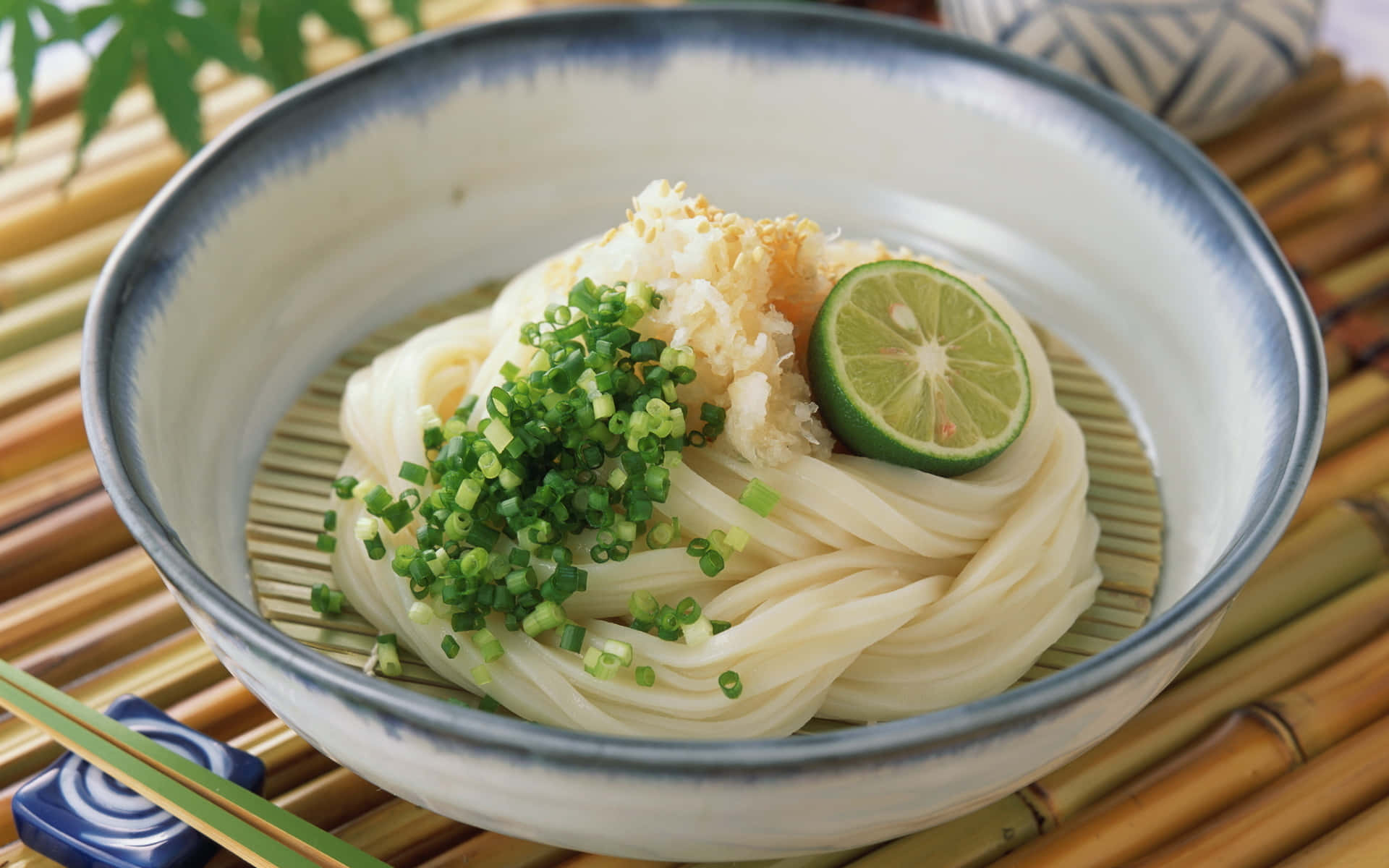 A Bowl Of Noodles With Lime And A Chopstick