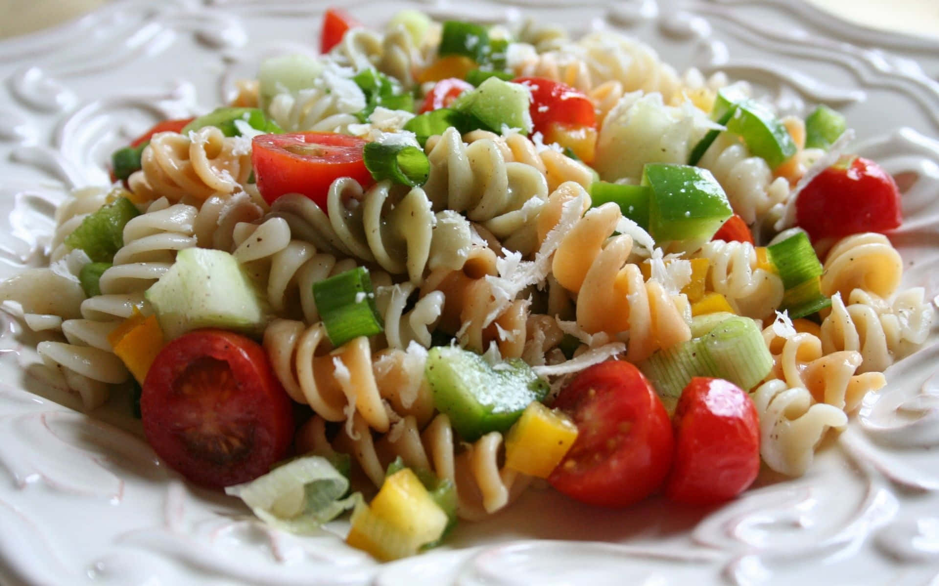 A Plate Of Pasta Salad With Tomatoes And Cucumbers