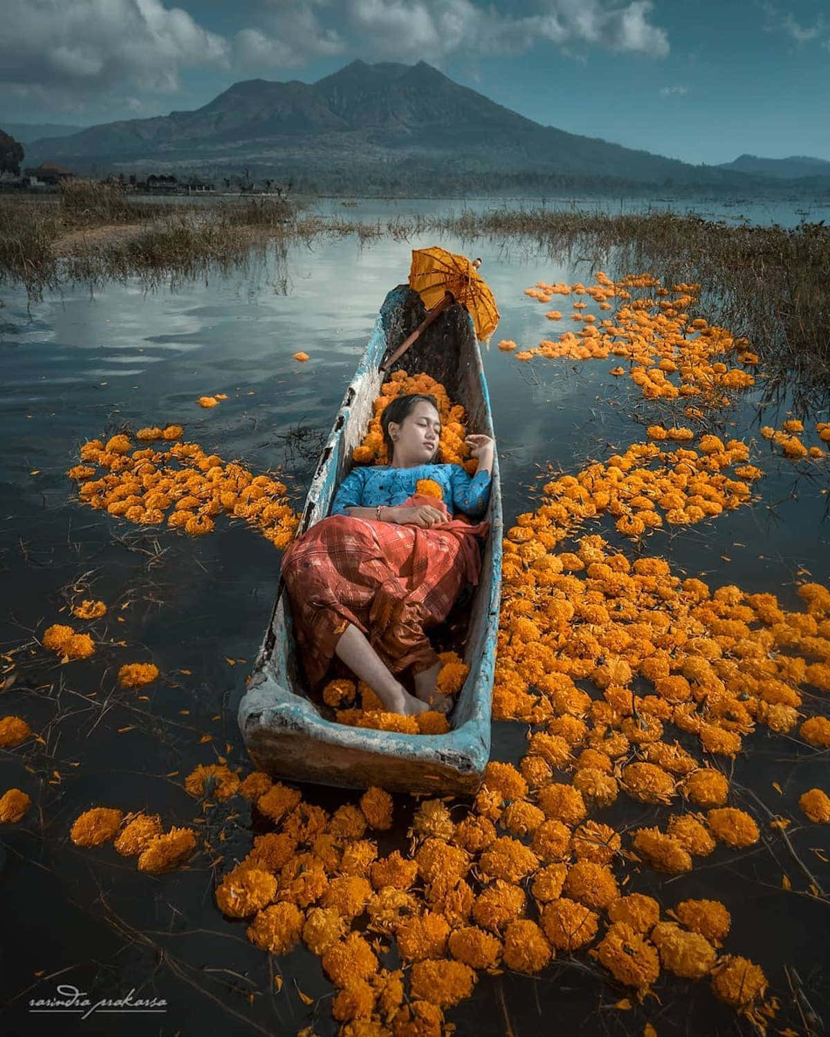 En kvinde ligger i en båd med orange blomster på den.