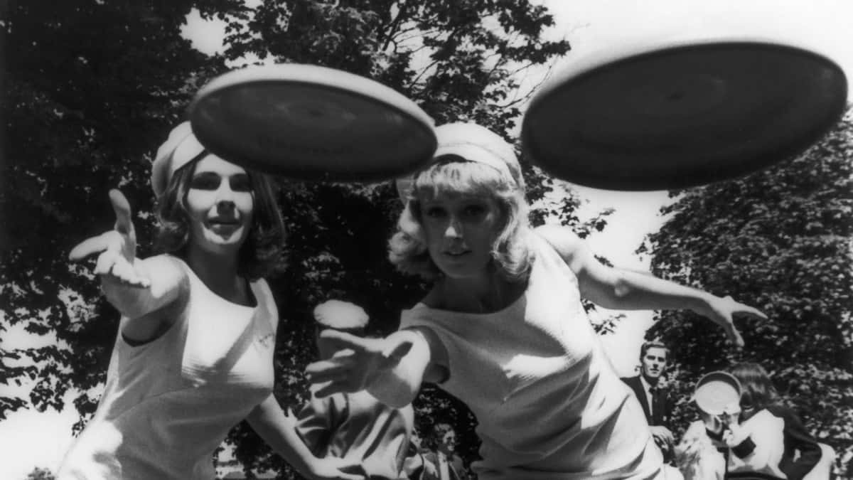 Tvåkvinnor Kastar Frisbees I Luften.