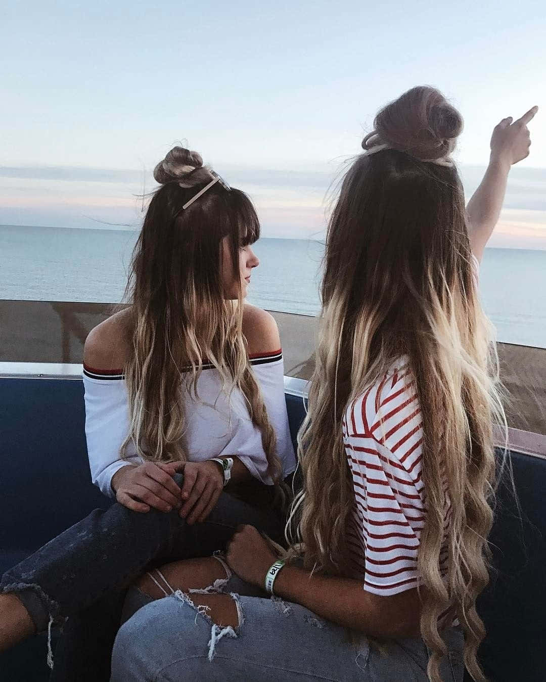 Two Girls Sitting On A Boat With Their Hair In A Bun