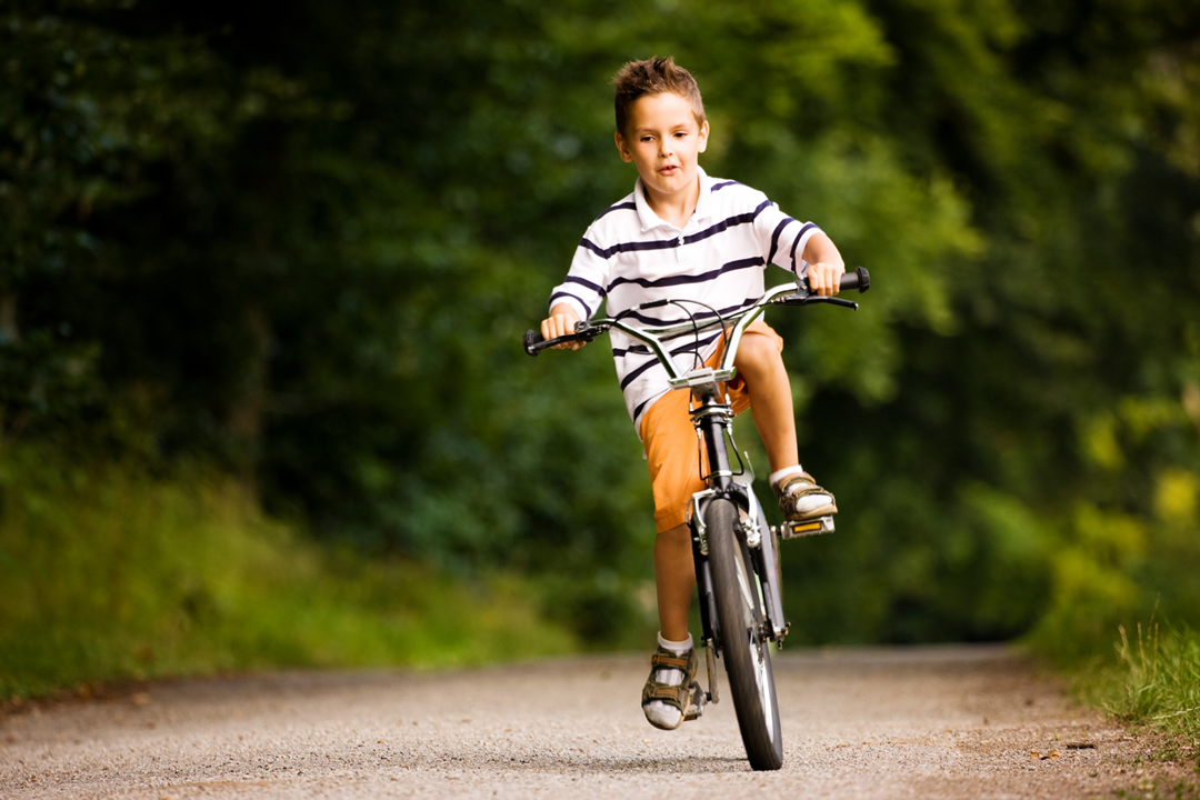 A Boy Riding A Bike Down A Road