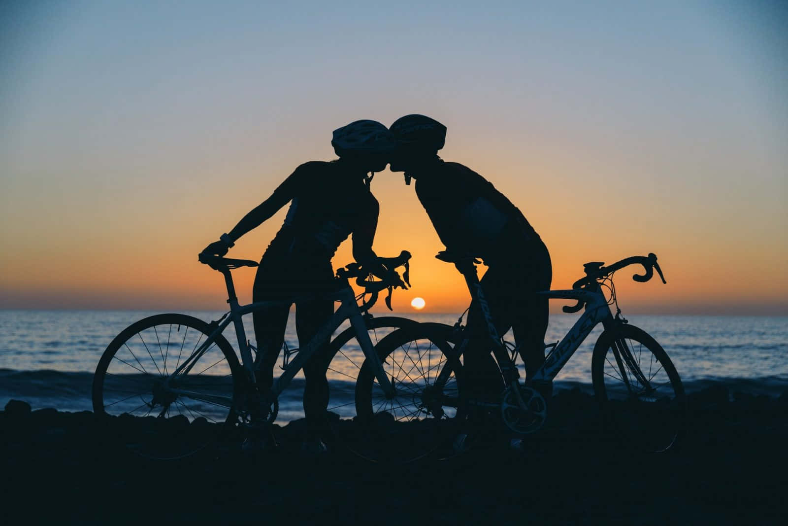 Zweipersonen, Die Bei Sonnenuntergang Auf Ihren Fahrrädern Küssen.