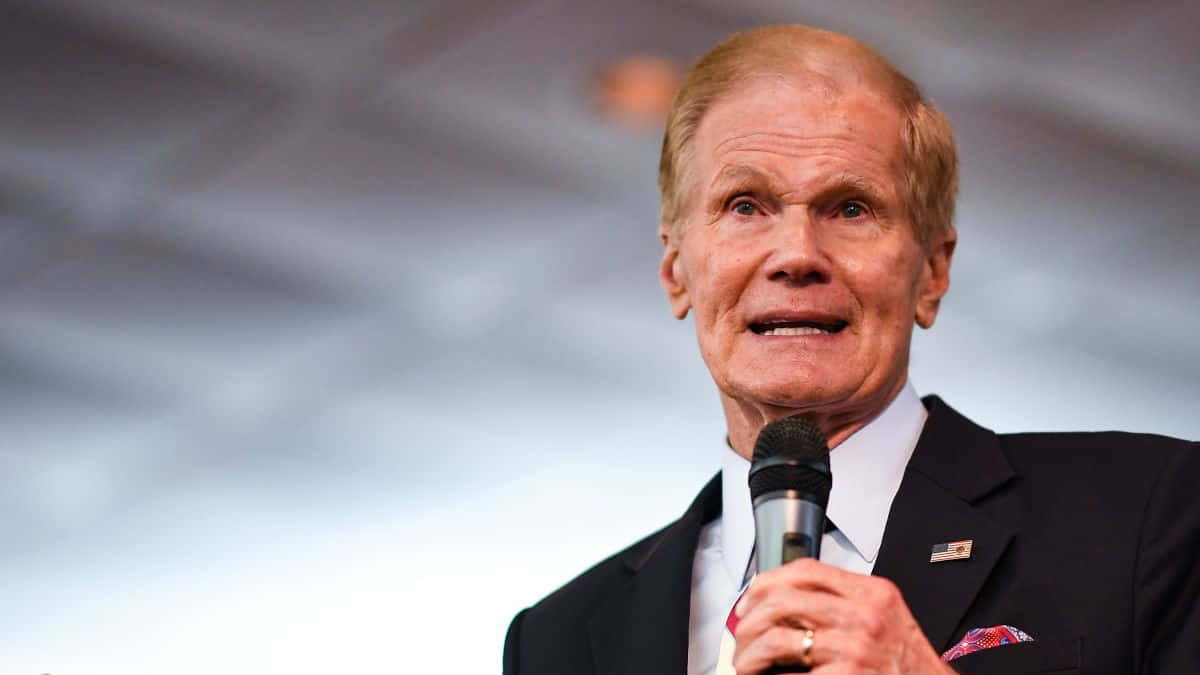 Bill Nelson With Microphone And Gray Backdrop Wallpaper
