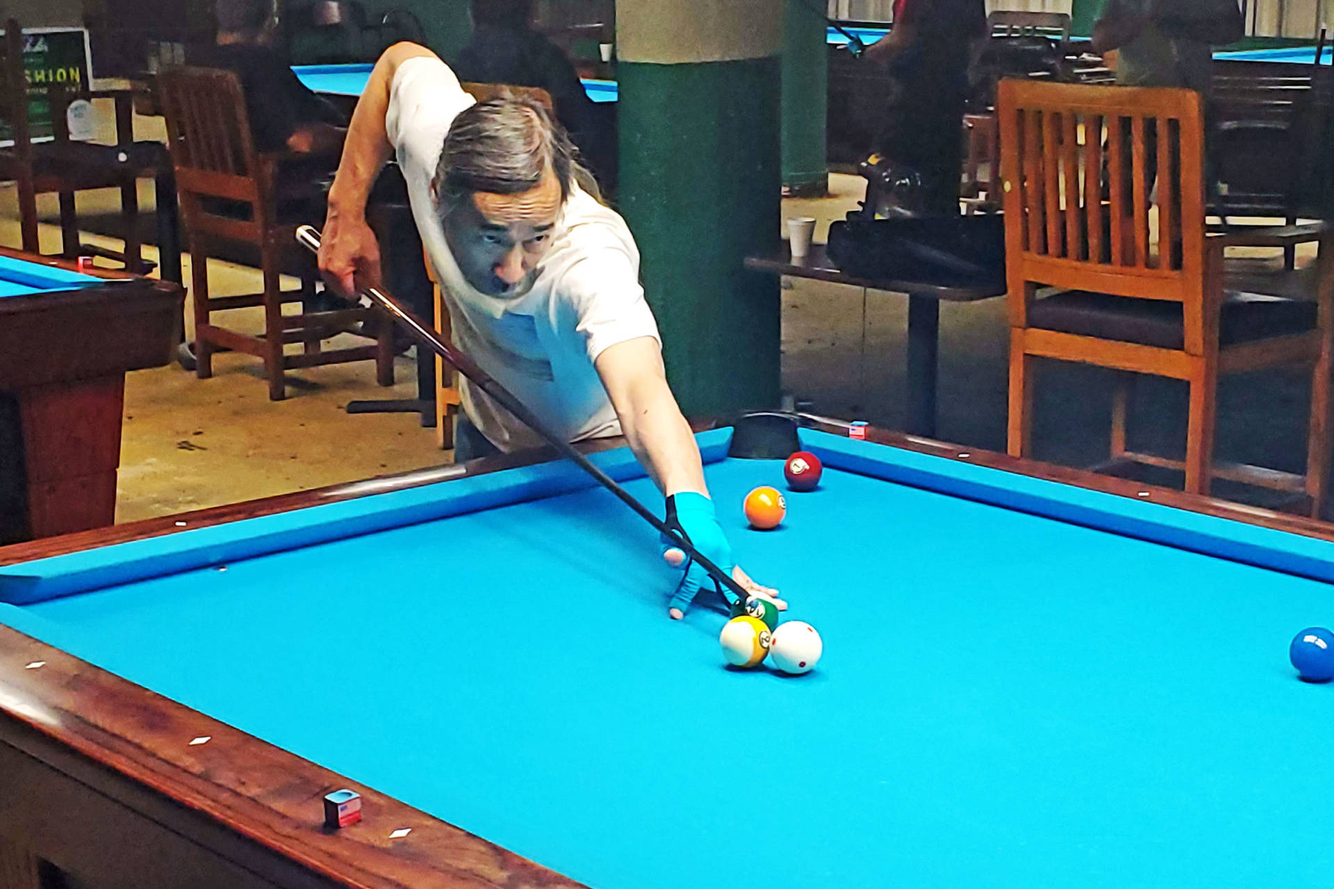 Mand spiller pool på blå bord på bar Wallpaper