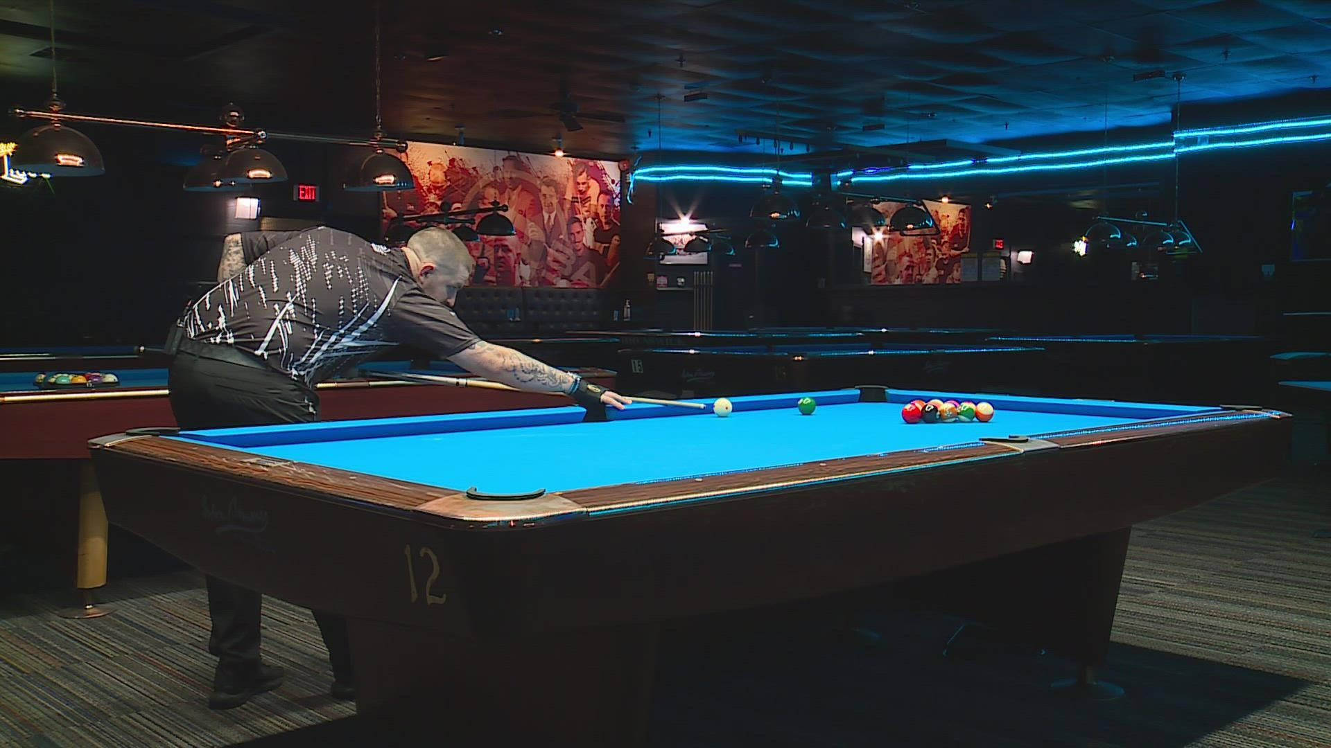 Professional billiards player in action on a vibrant blue pool table. Wallpaper
