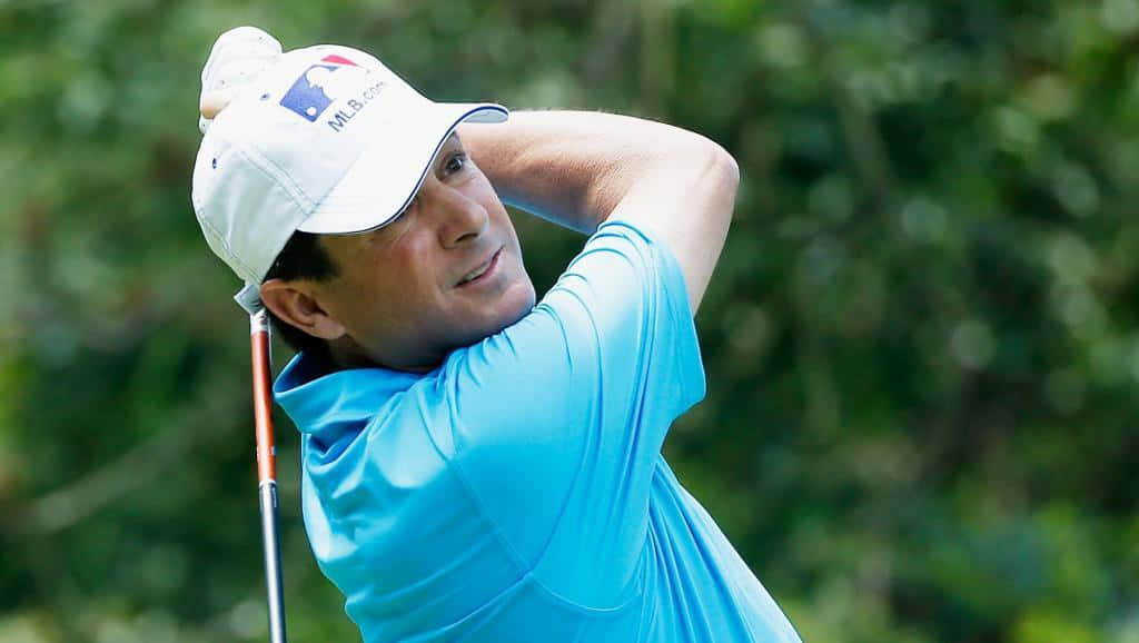 Billy Andrade svinger en golfklub mod et struktureret blåt baggrund Wallpaper