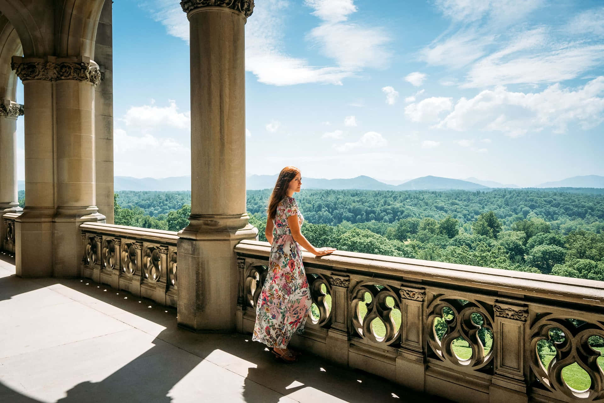 A Woman Is Standing On A Balcony Overlooking A Mountain