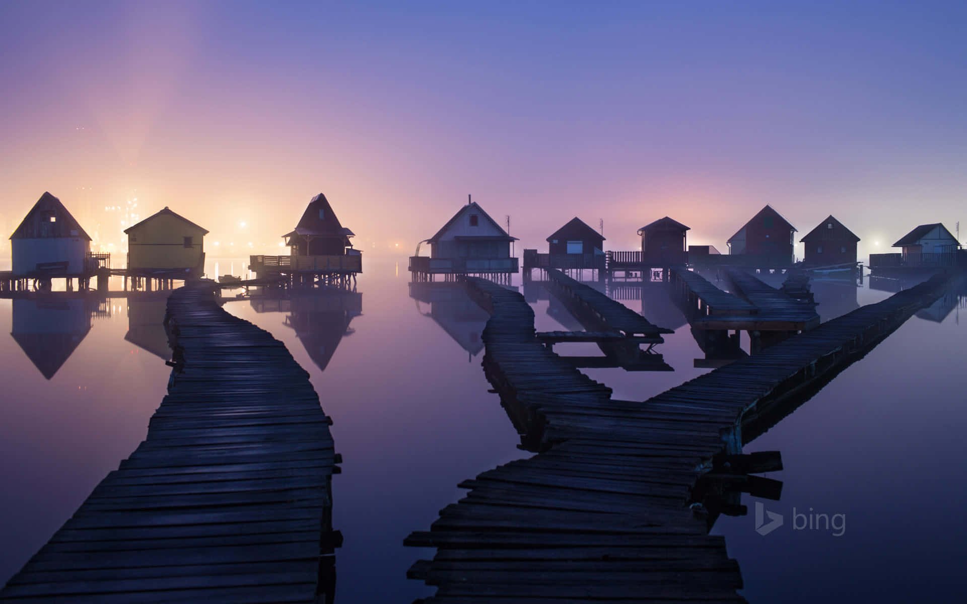 A Group Of Wooden Houses On A Dock In The Water