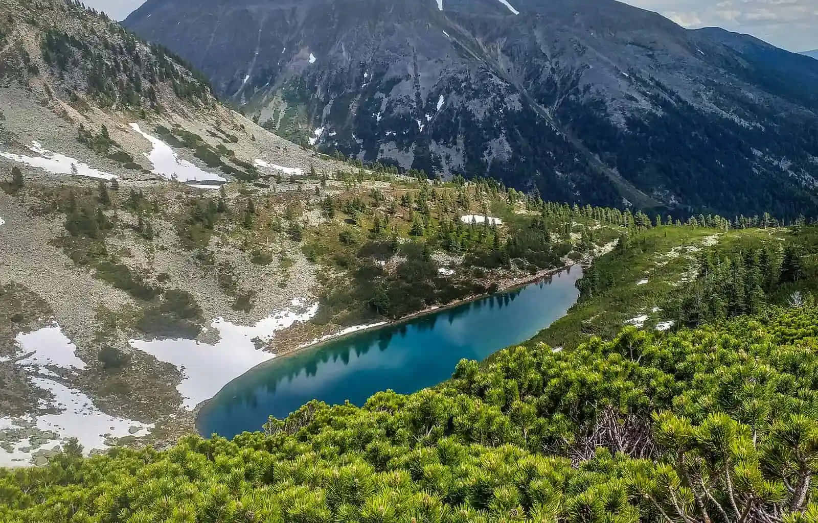 A Lake In The Mountains With Trees Surrounding It