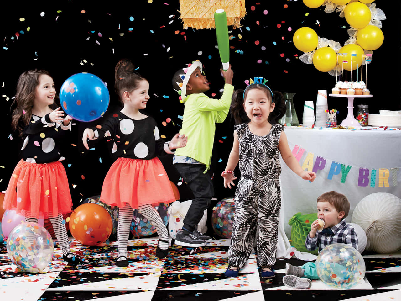 A Group Of Children Playing With Balloons And Confetti
