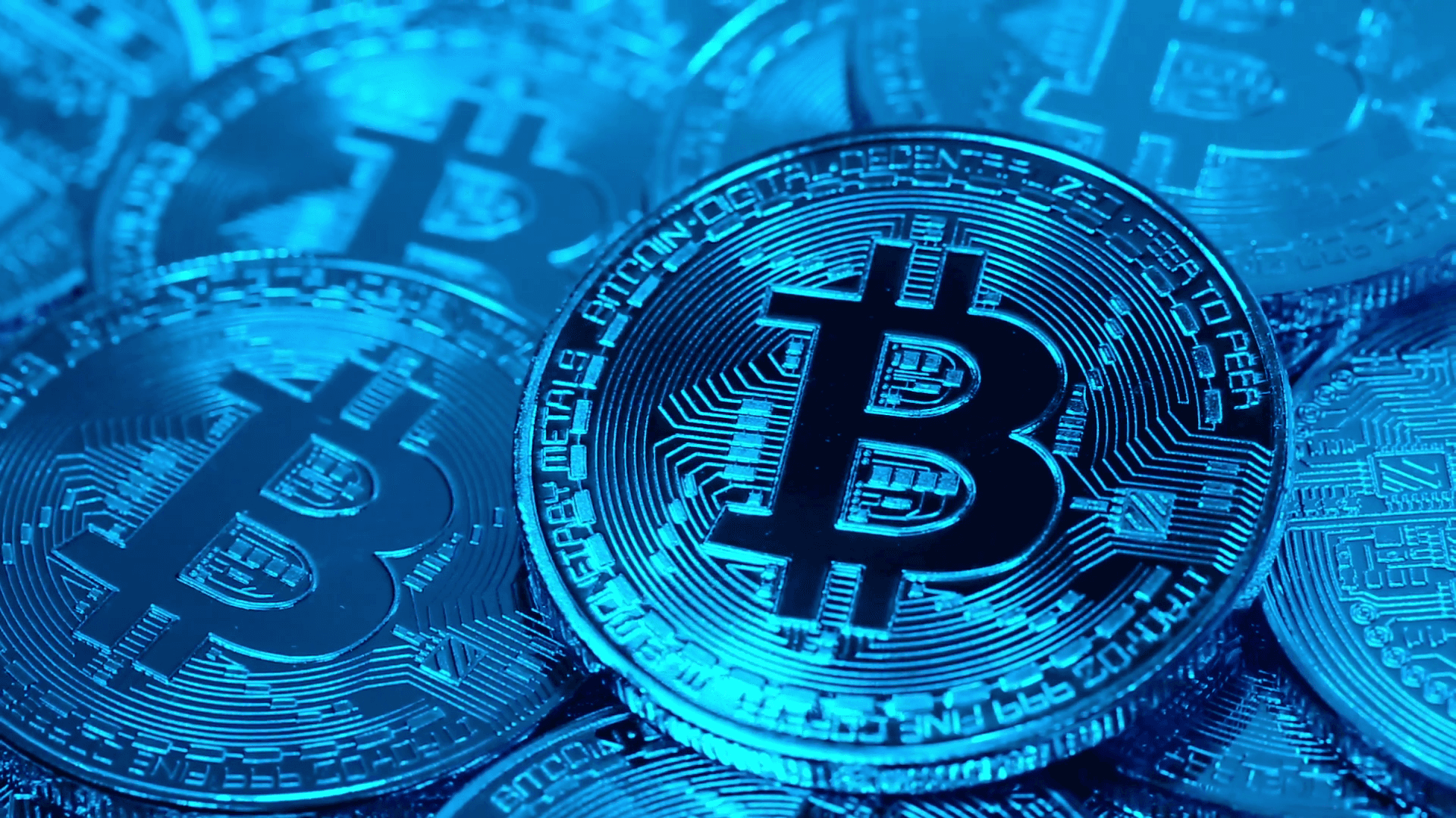 bitcoins are stacked in a blue background — Shiny blue Bitcoin coins with circuit board patterns stacked in a close-up shot.