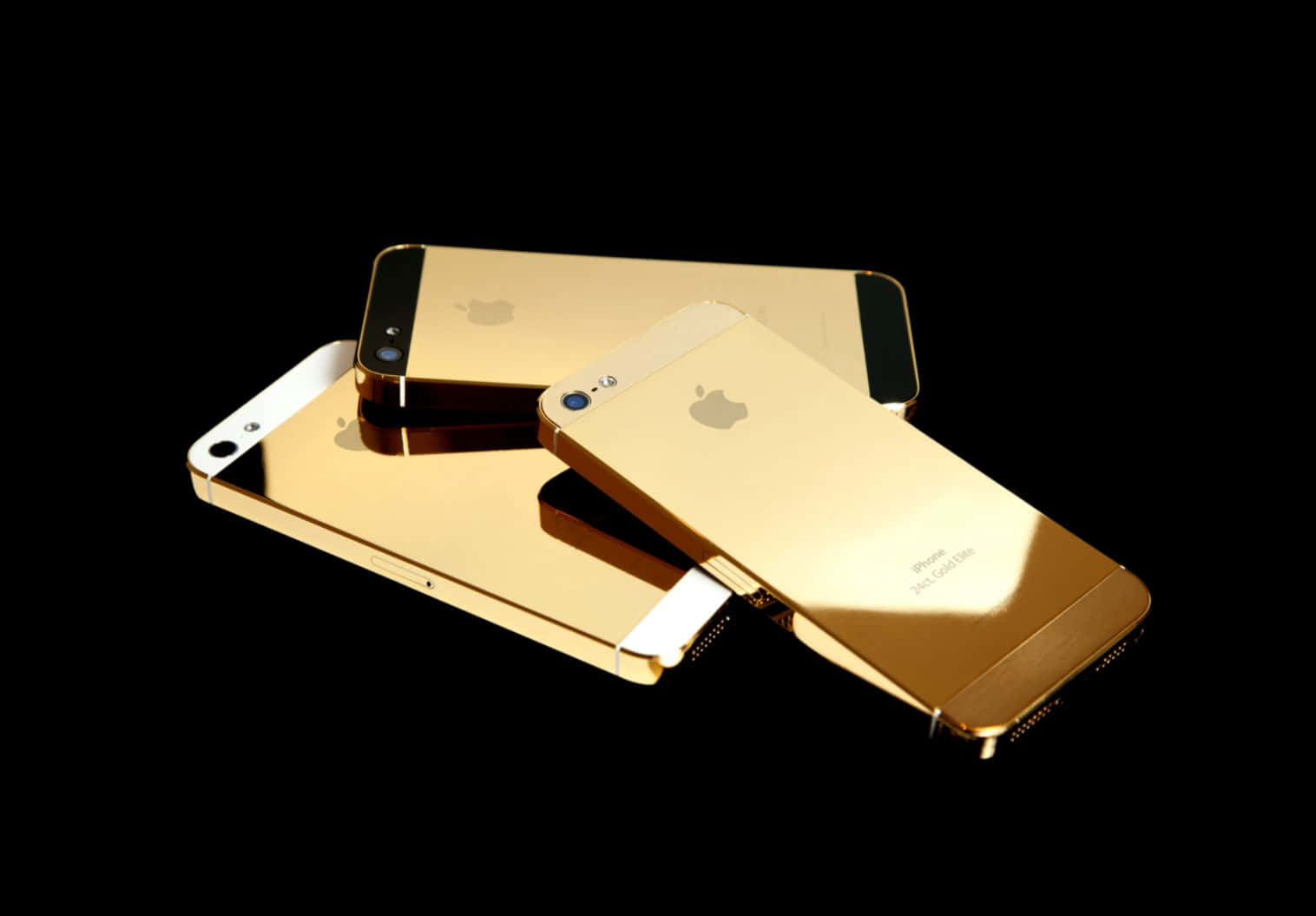 Three Gold Iphones On A Black Background Wallpaper