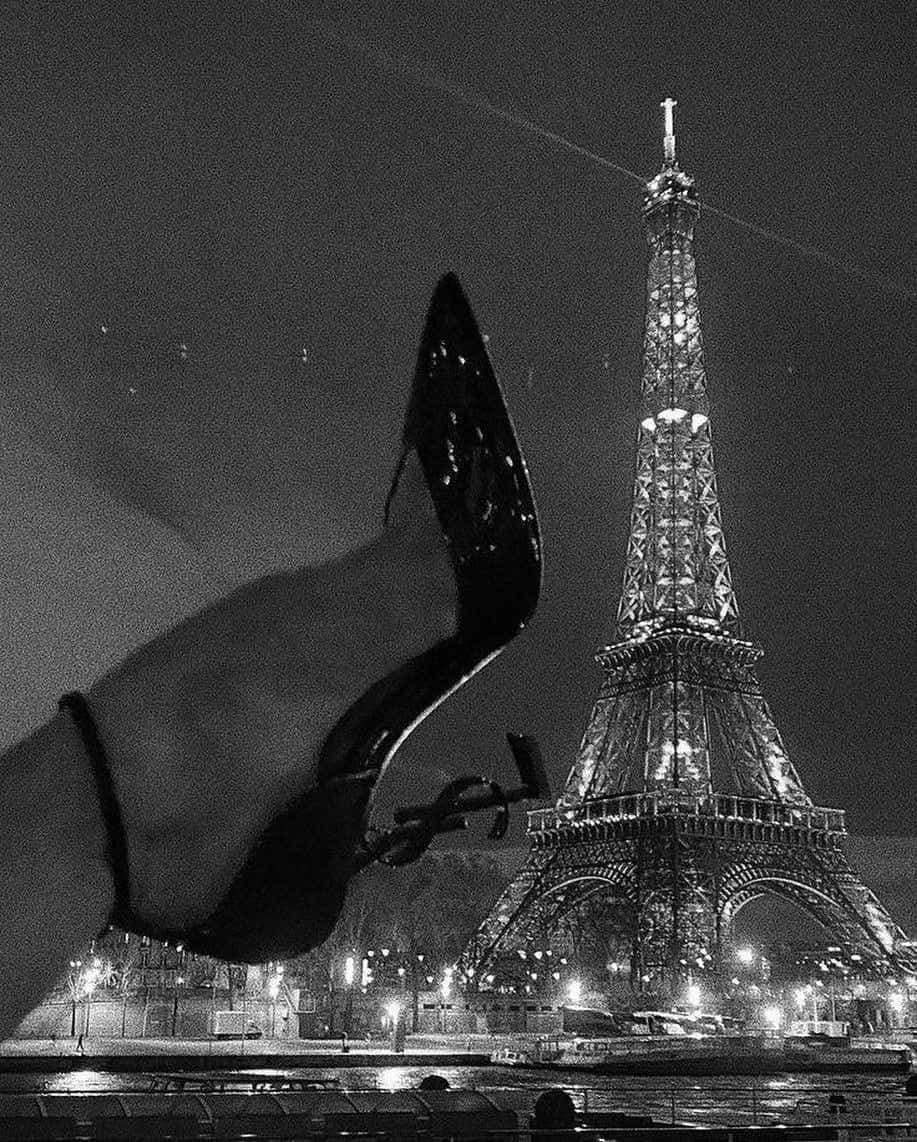 A Woman's Foot Is Shown In Front Of The Eiffel Tower