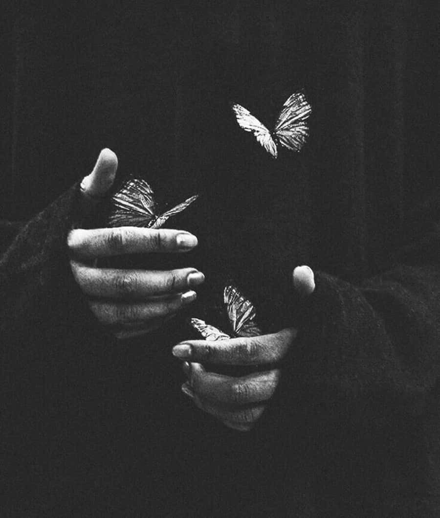 A Black And White Photo Of A Person Holding Butterflies