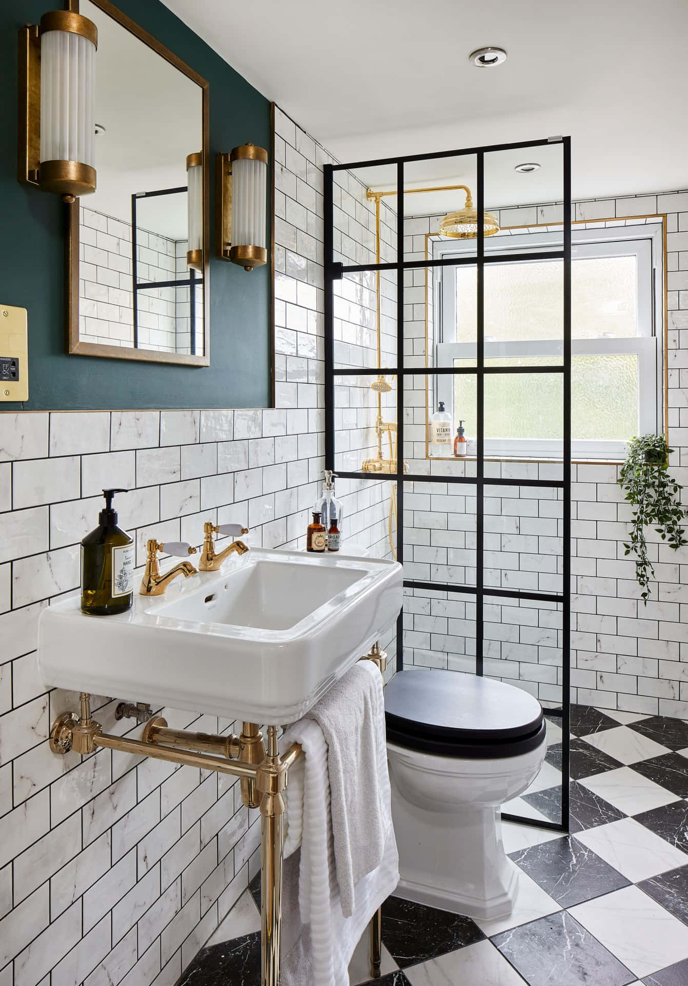 A Bathroom With Black And White Tile And A Gold Sink