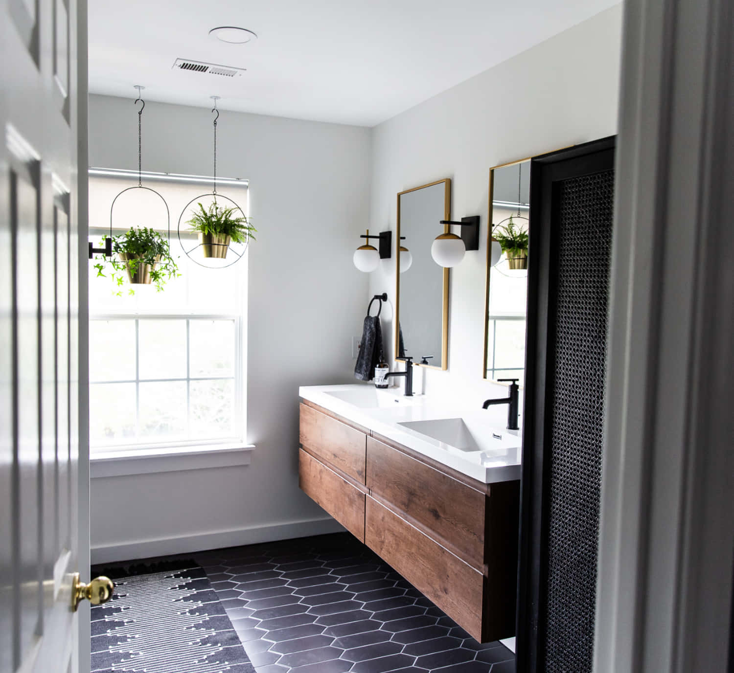 A Bathroom With Black And White Tile And Wooden Cabinets