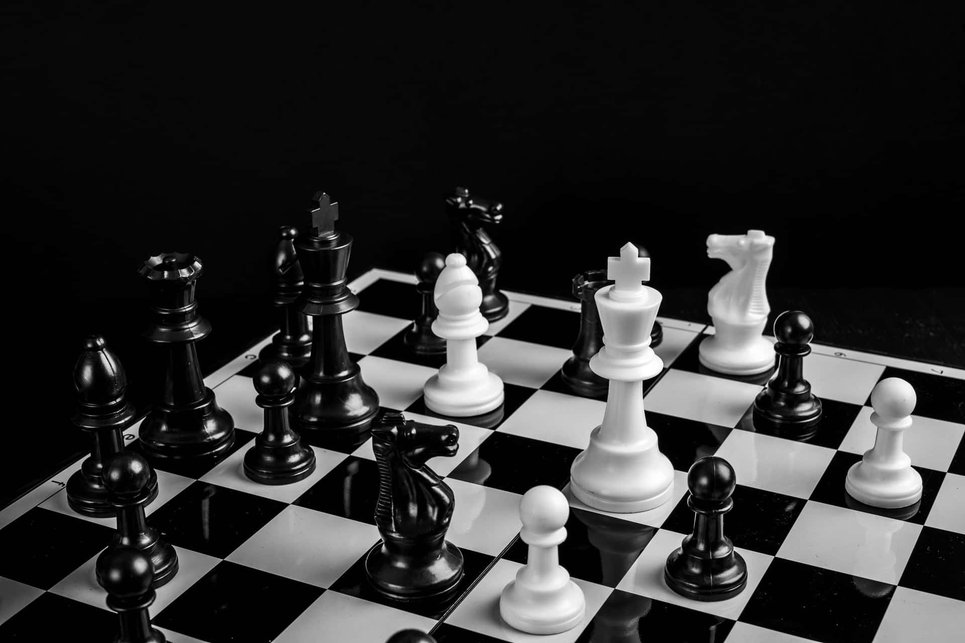 Classic Black and White Chess Pieces Set Up on a Board Wallpaper