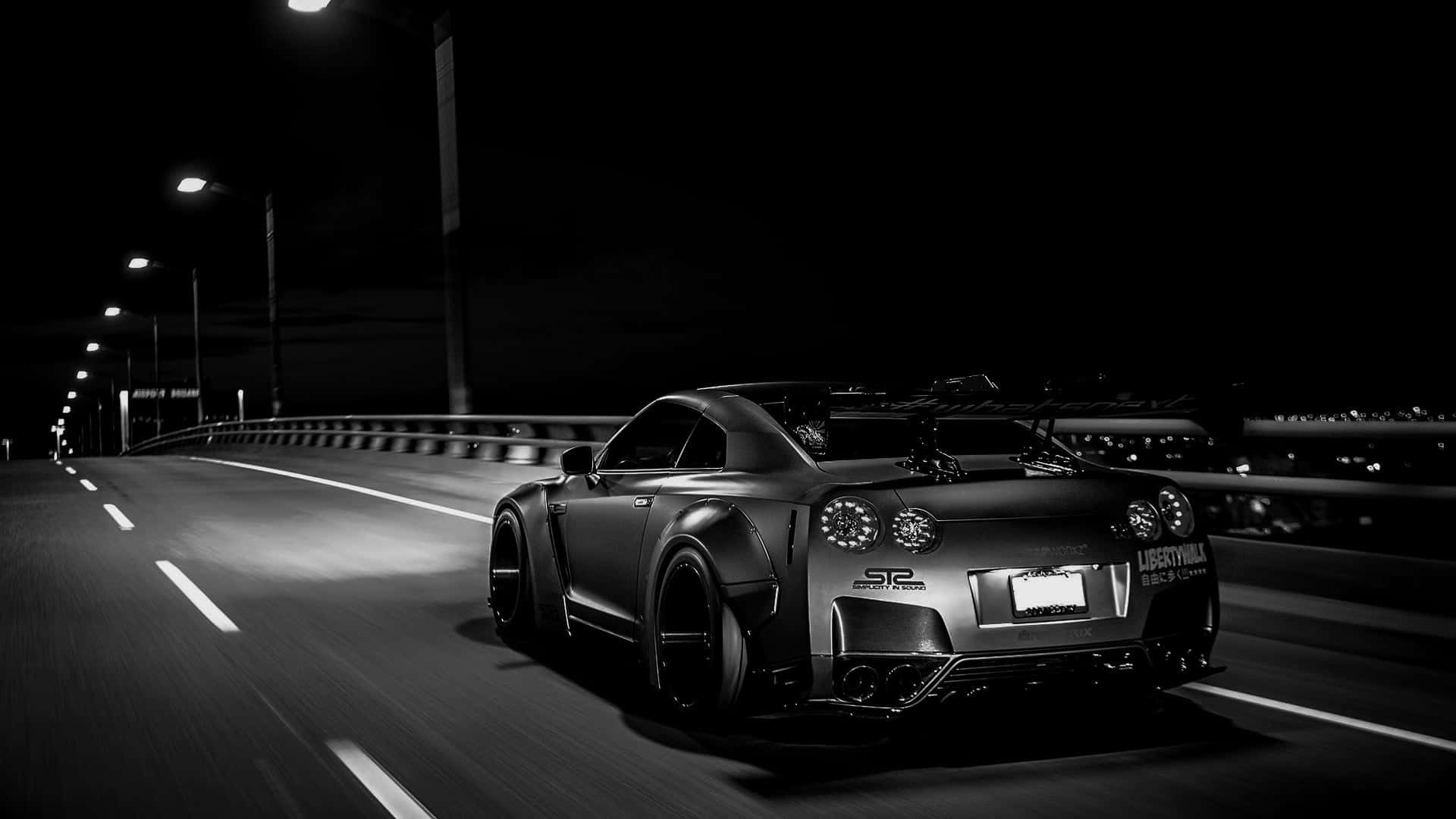 A Black And White Image Of A Sports Car Driving On A Bridge Wallpaper