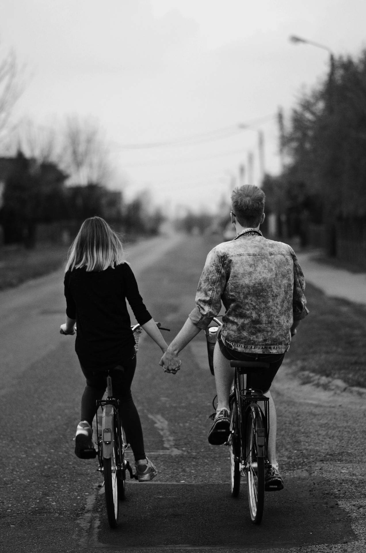 Black And White Holding Hands While Riding Bikes Wallpaper